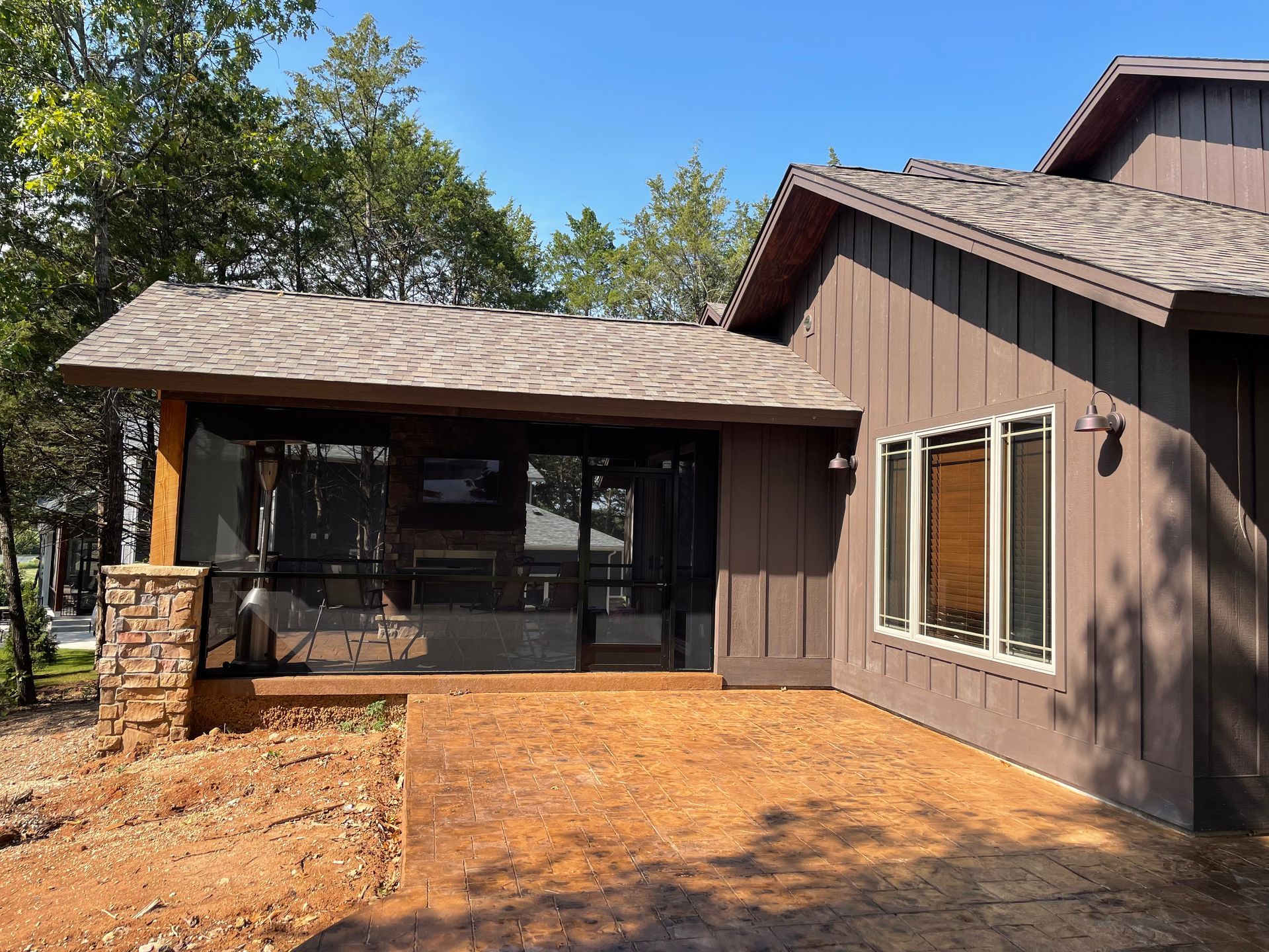A brown house with a screened in porch and windows