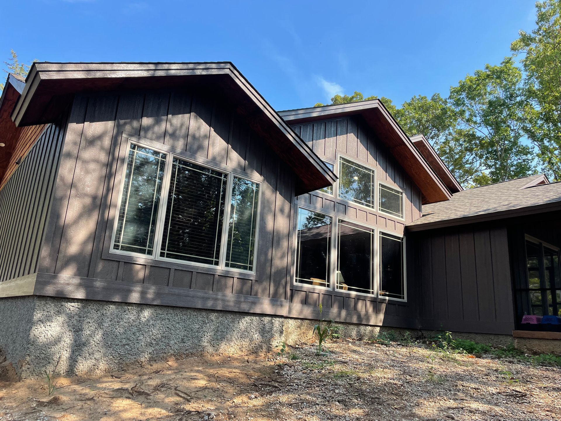 A large house with a lot of windows is sitting on top of a dirt hill.