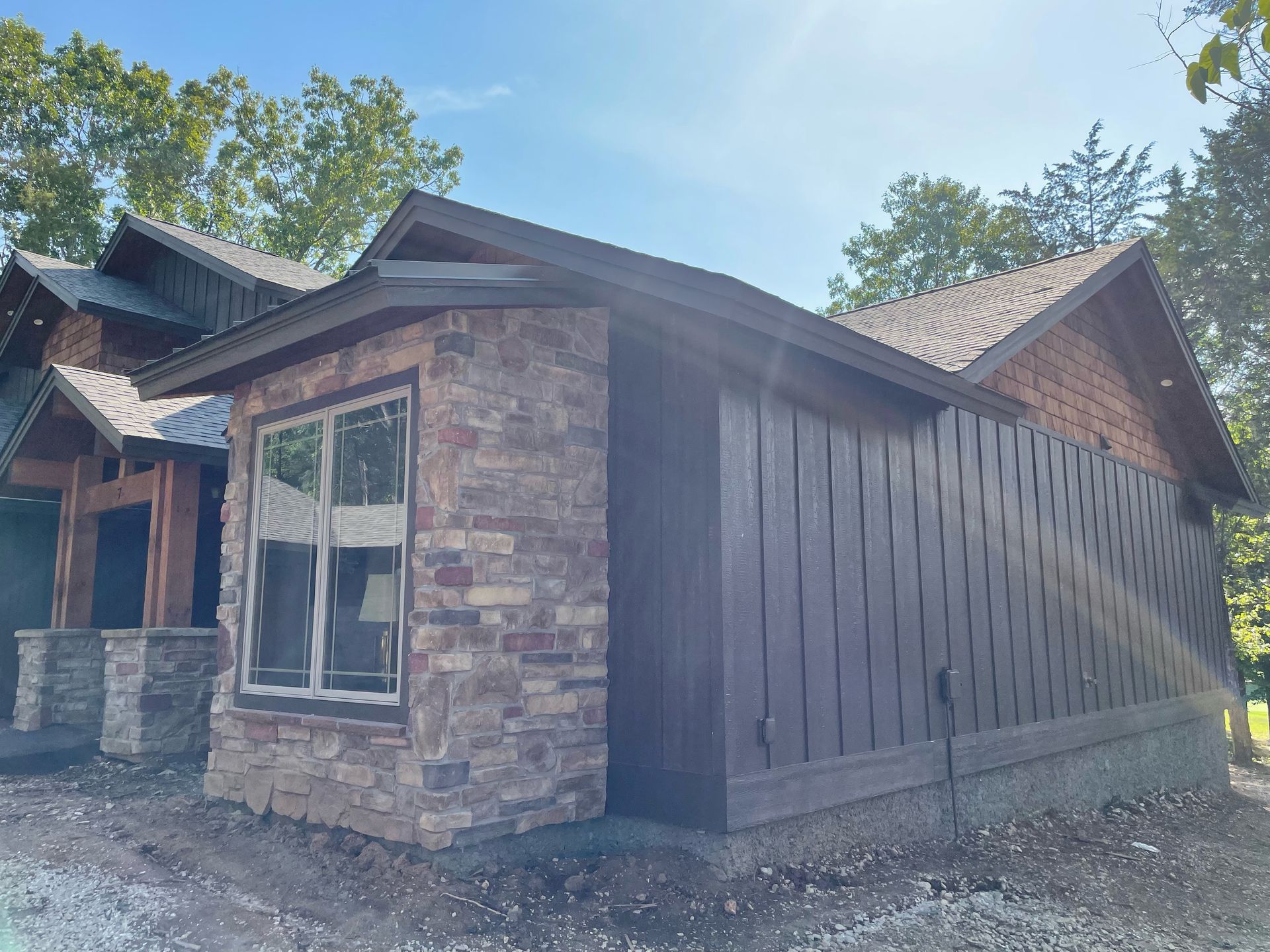 A house with a stone wall and a wooden fence is being built.