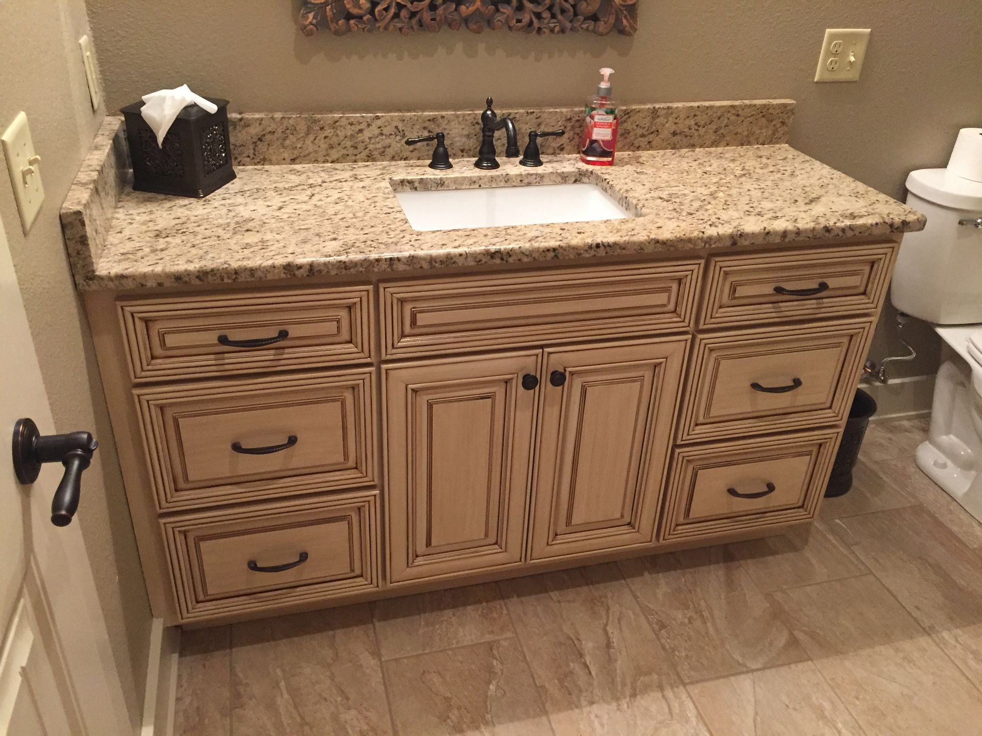 A bathroom with a sink , drawers , and a toilet.