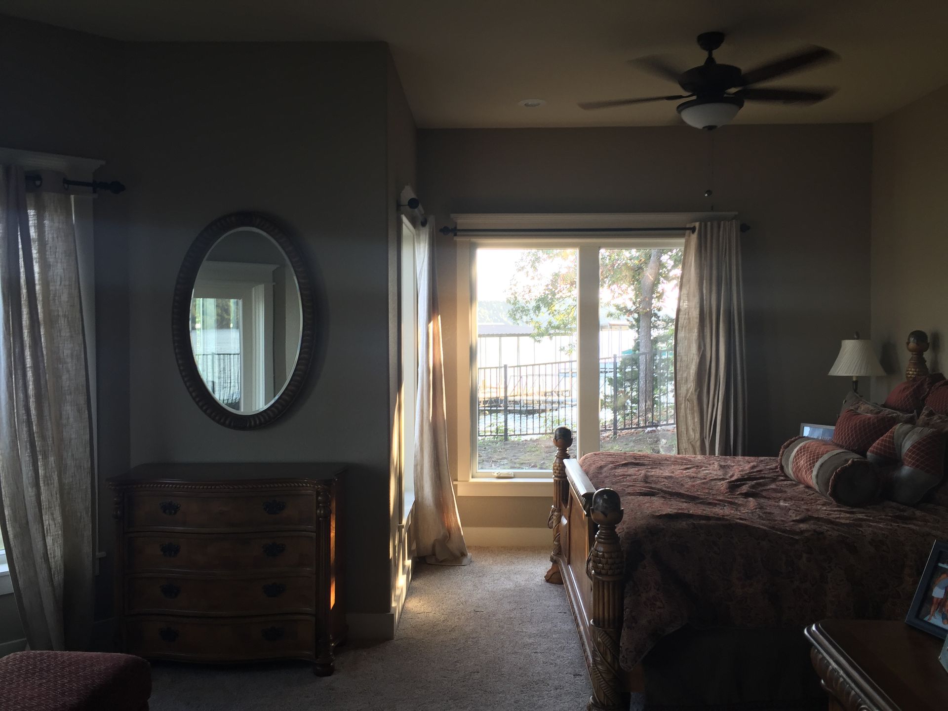 A bedroom with a large bed a dresser a mirror and a ceiling fan