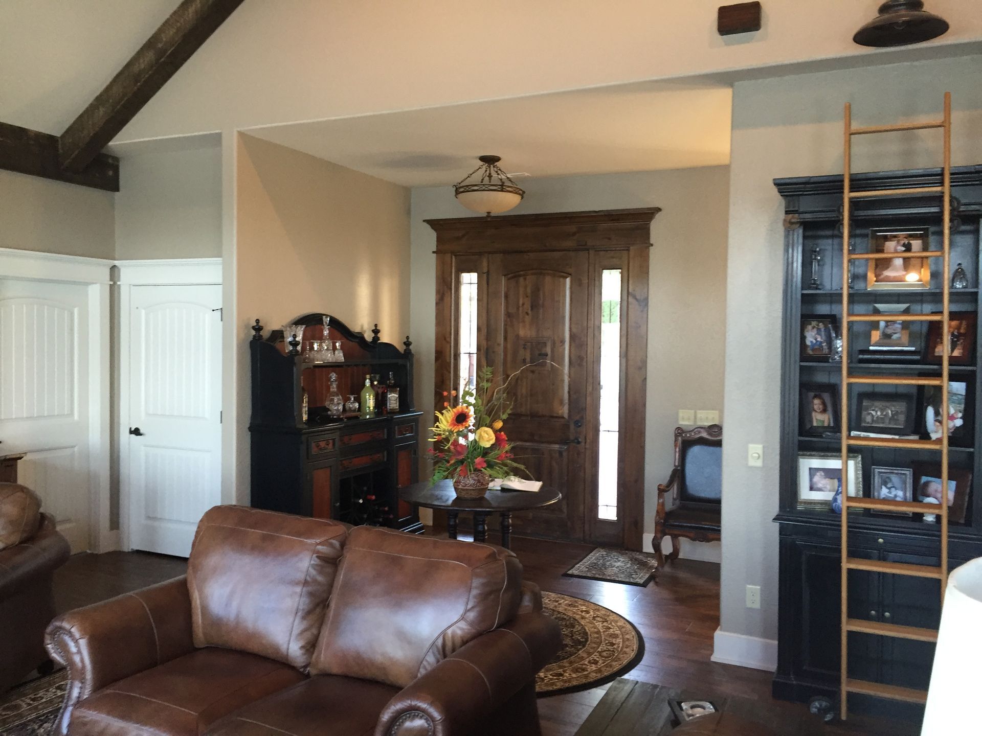 A living room with a brown leather couch and a ladder