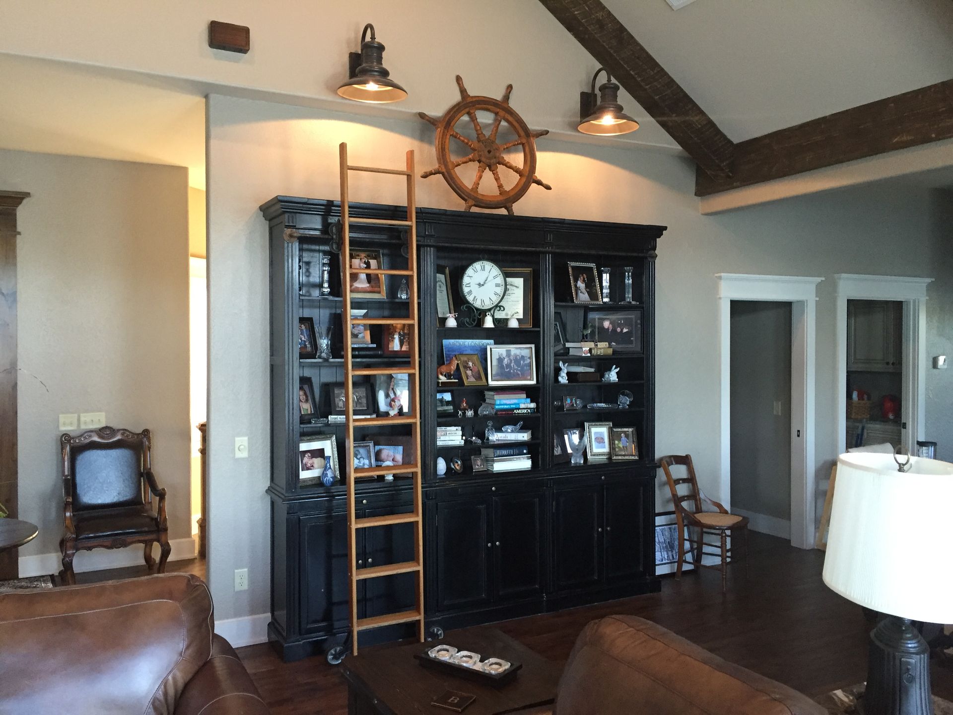 A living room with a ladder and a ship wheel on the wall