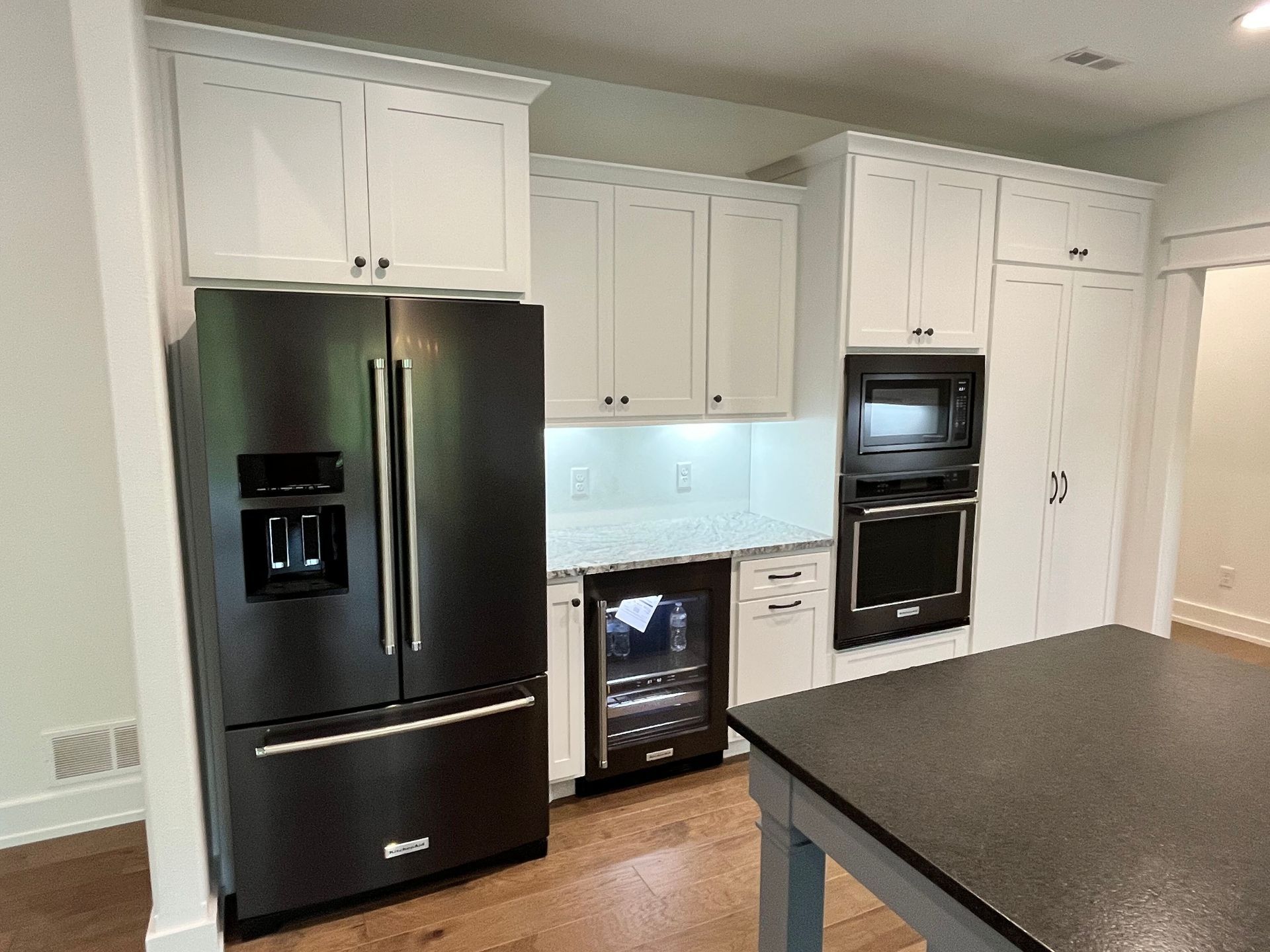 A kitchen with a black refrigerator and white cabinets