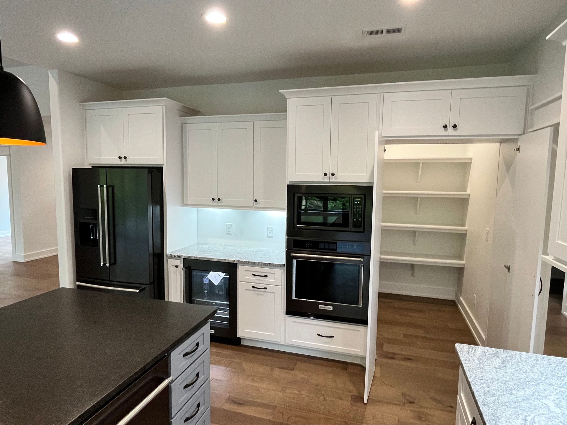 A kitchen with white cabinets , black appliances , a refrigerator and a microwave.