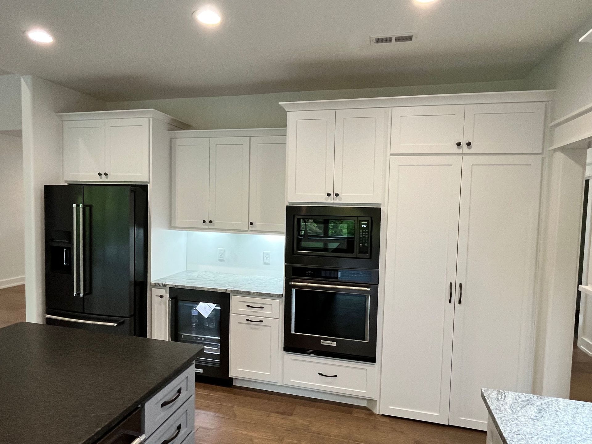 A kitchen with white cabinets , black appliances , a refrigerator and a microwave.