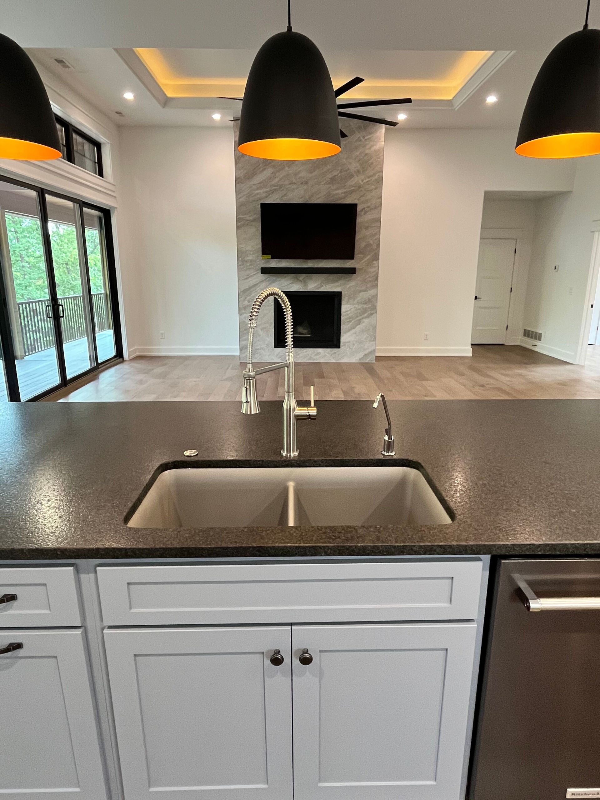 A kitchen with a sink and a television on the wall