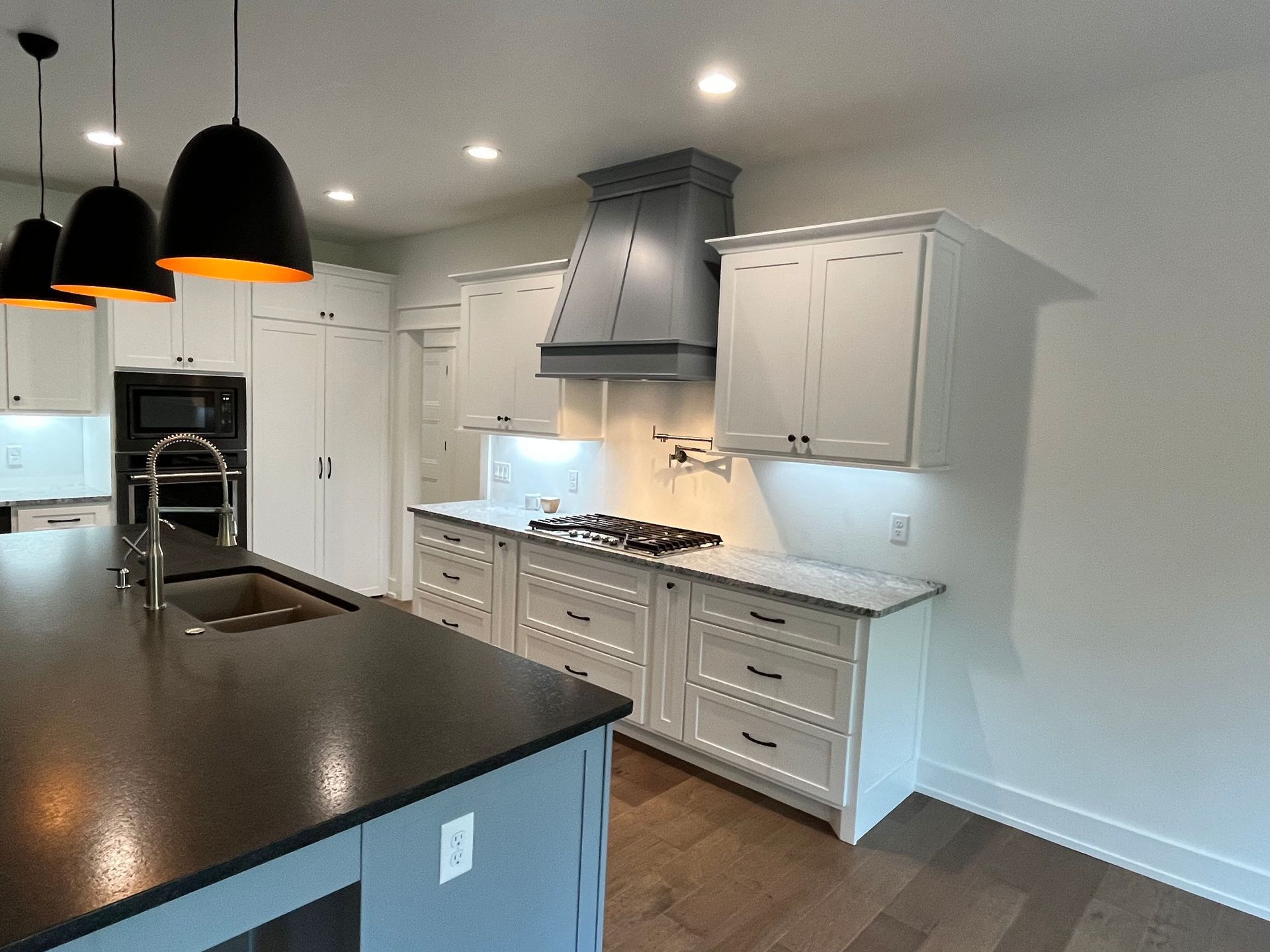 A kitchen with white cabinets and black counter tops