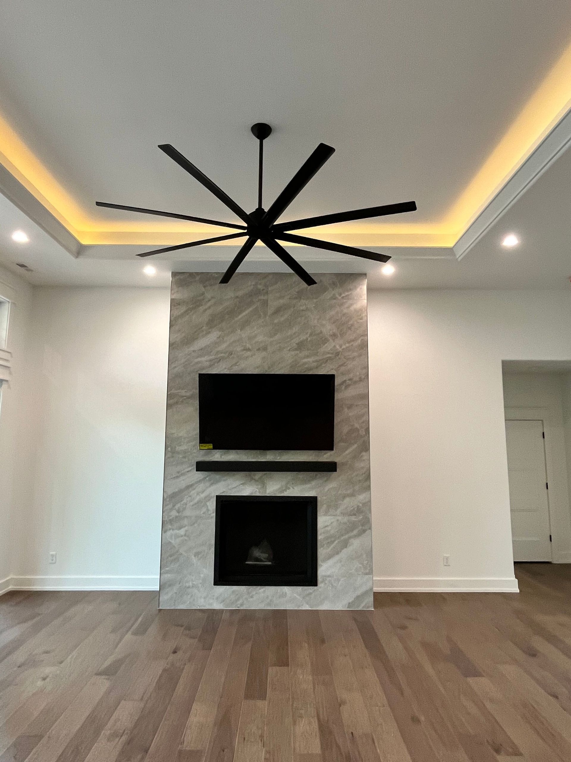 A living room with a fireplace and ceiling fan