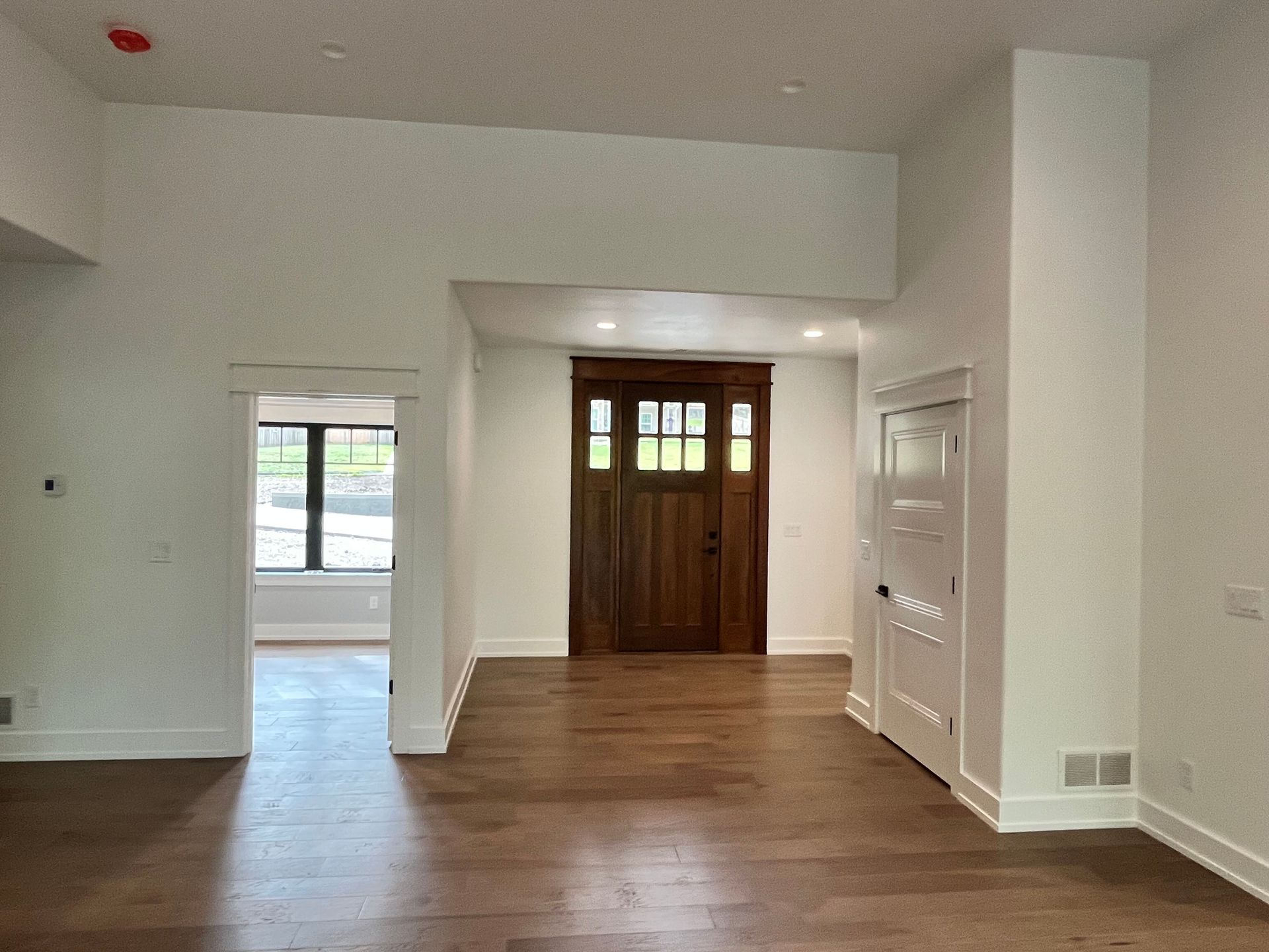 A large empty room with hardwood floors and a wooden door