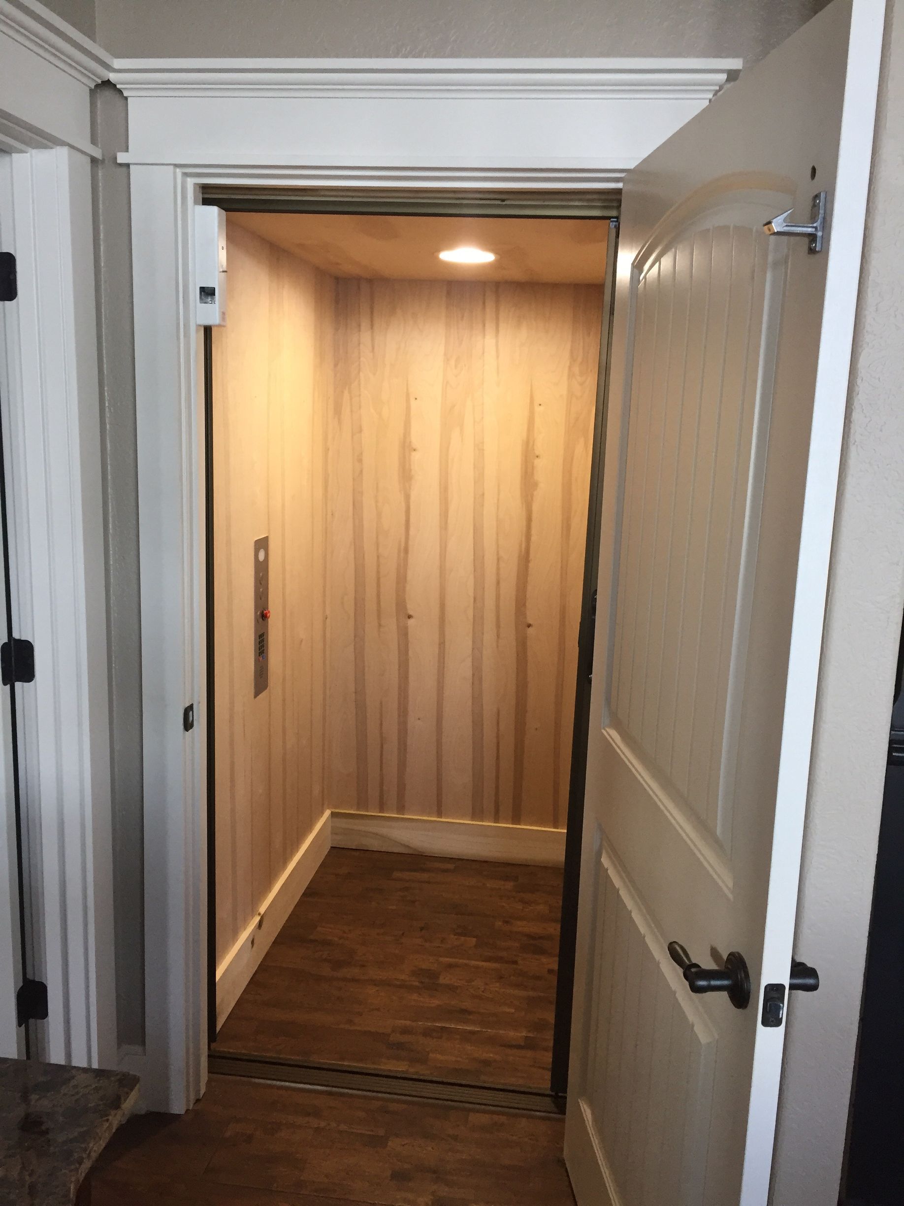 A wooden elevator with a door open in a room.