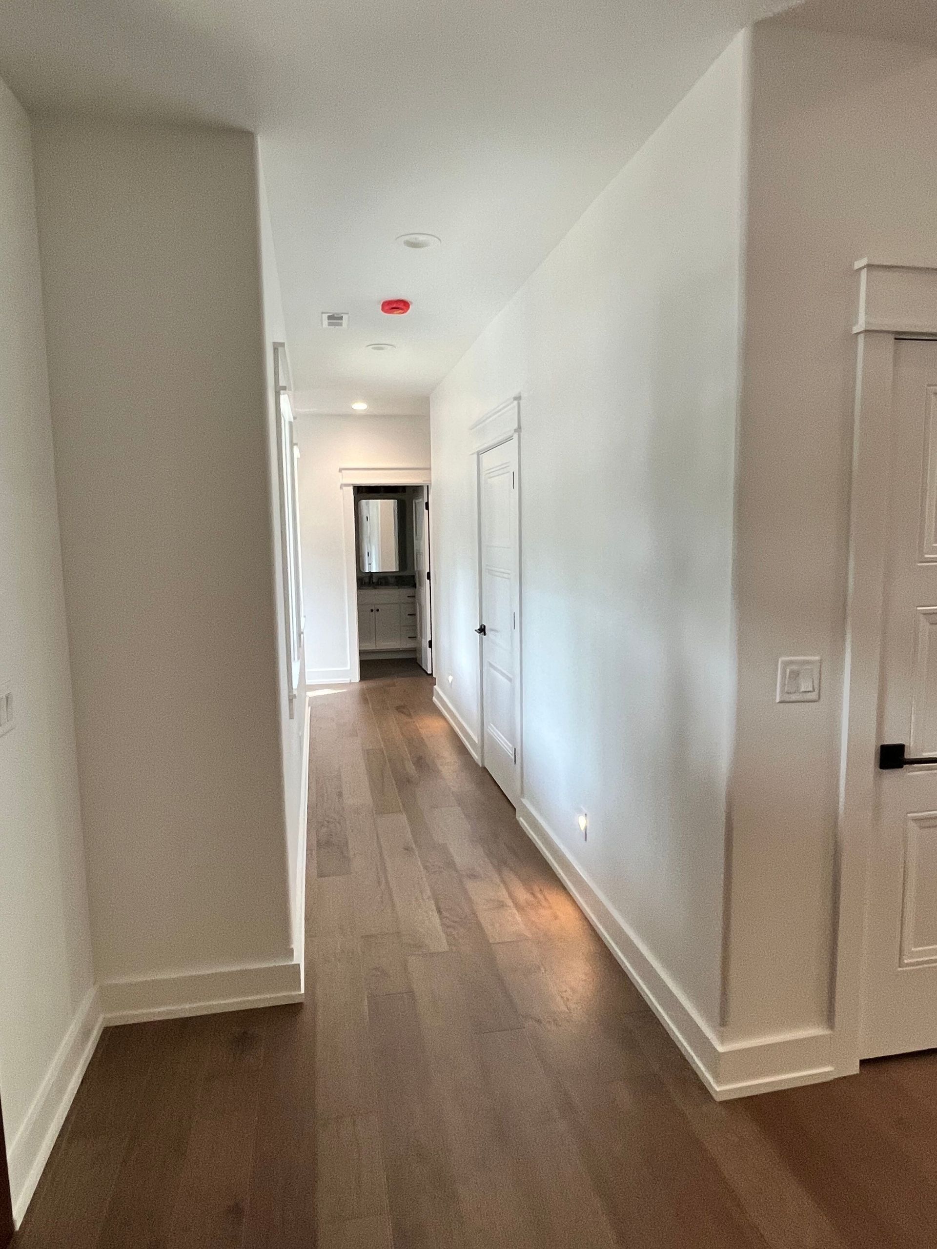 A long hallway with hardwood floors and white walls