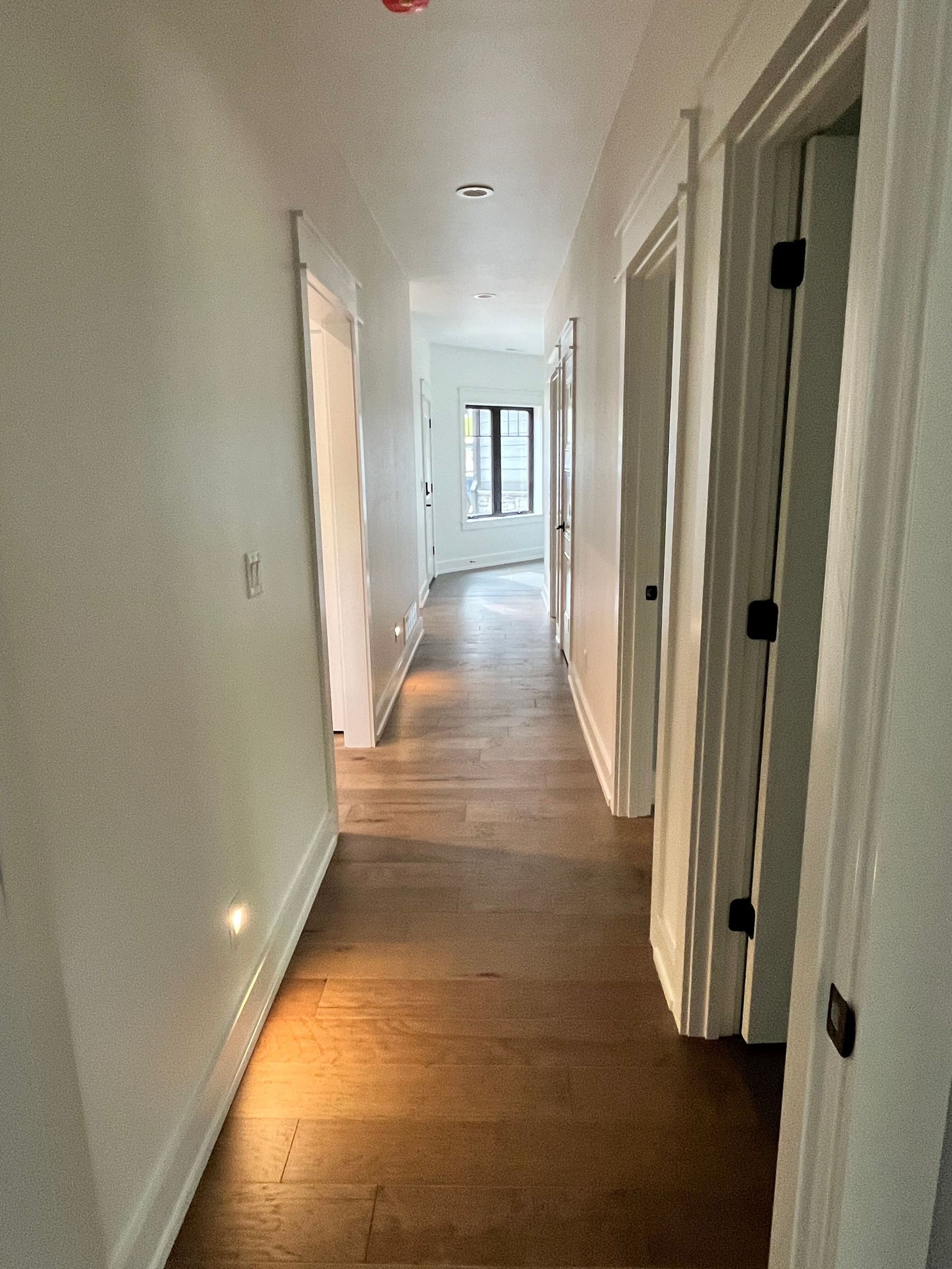 A long hallway with wooden floors and white walls in a house.