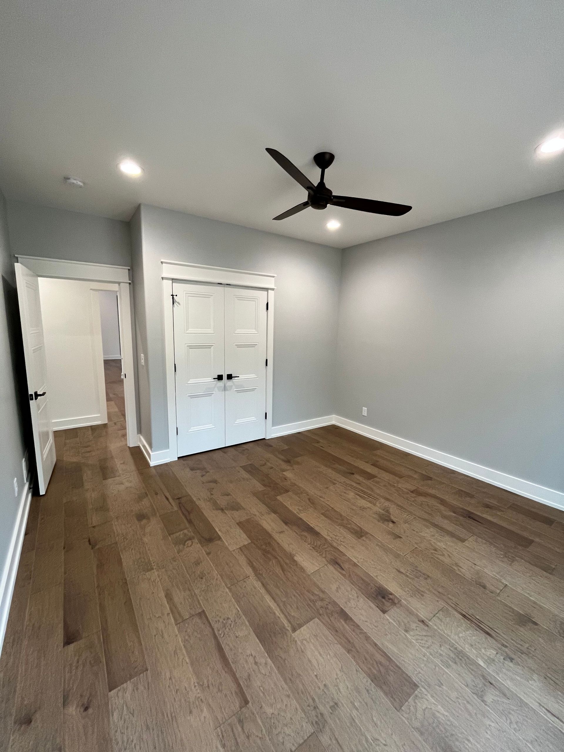 An empty room with hardwood floors and a ceiling fan.