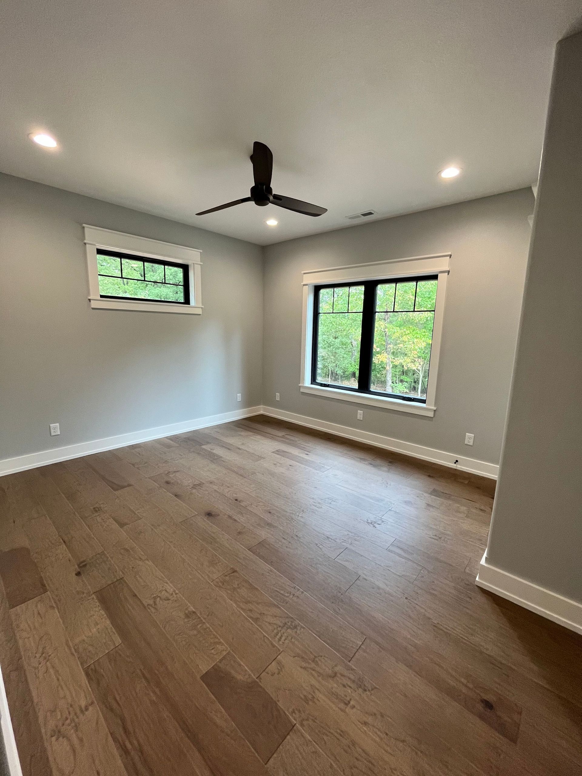 An empty room with hardwood floors and a ceiling fan.