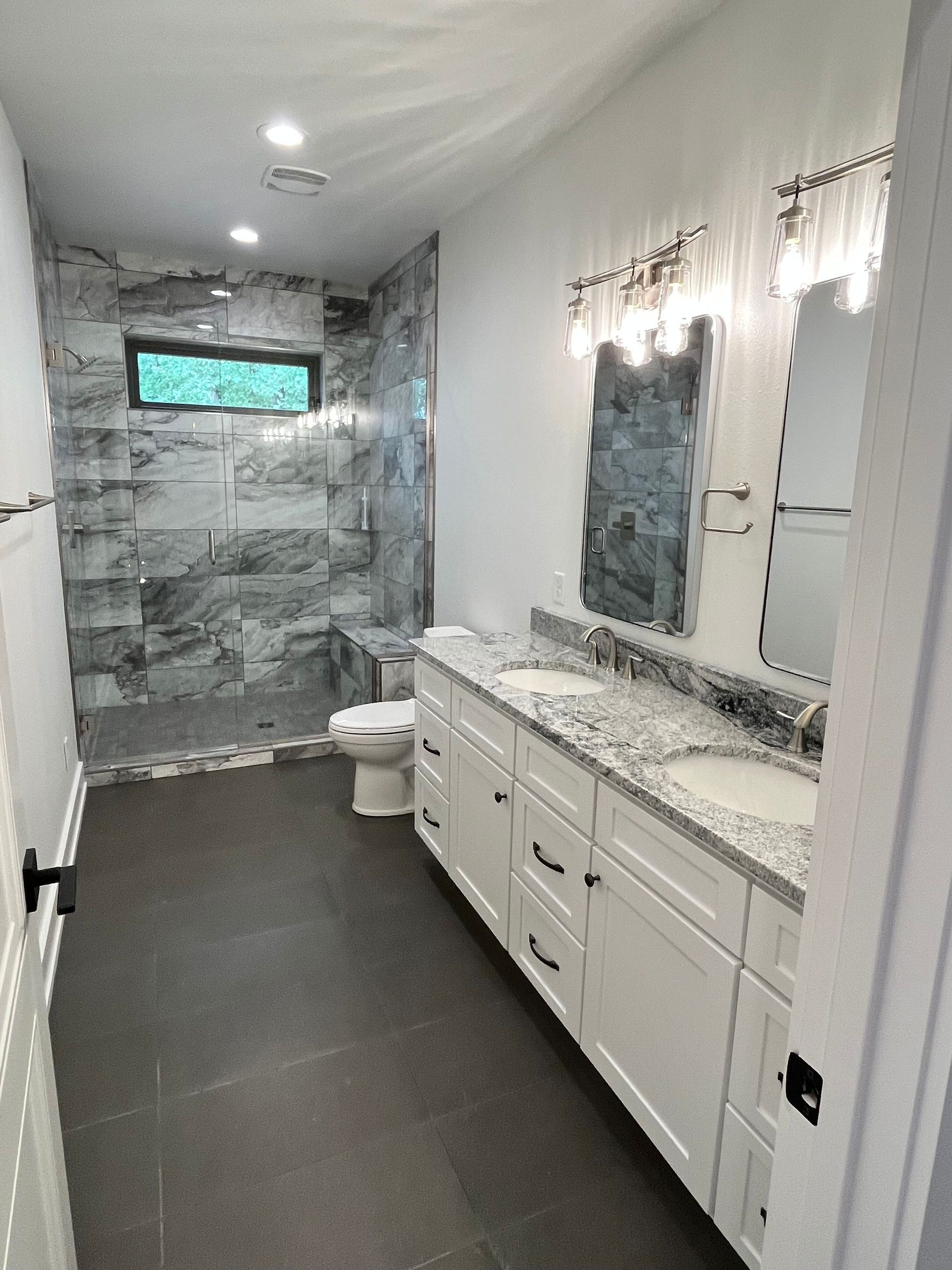 A bathroom with a toilet , sink , mirror and shower.