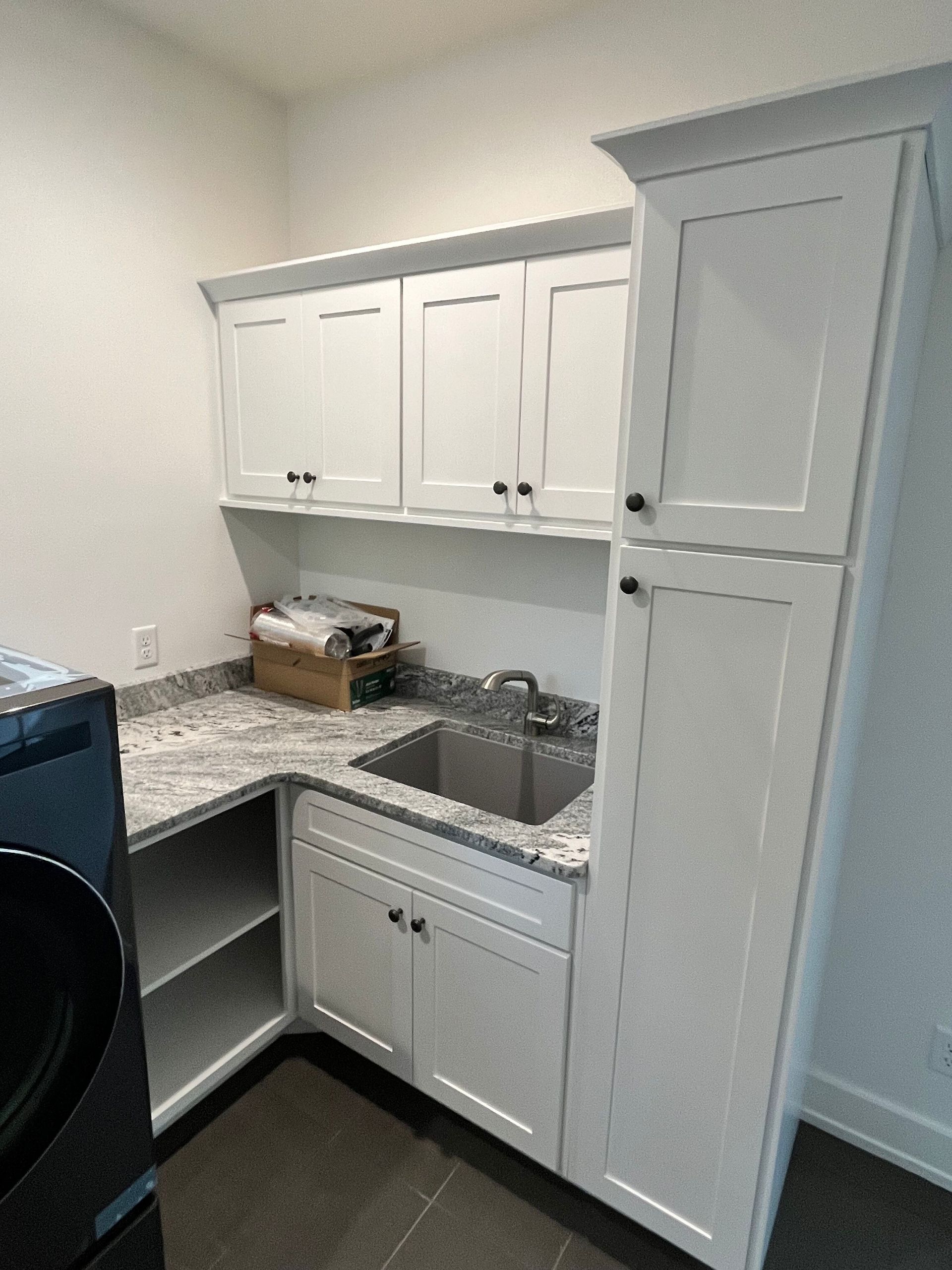 A laundry room with white cabinets , a sink , and a washer and dryer.