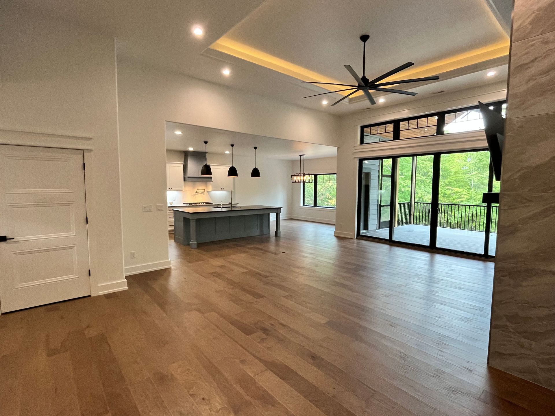 A large empty room with hardwood floors and a ceiling fan.