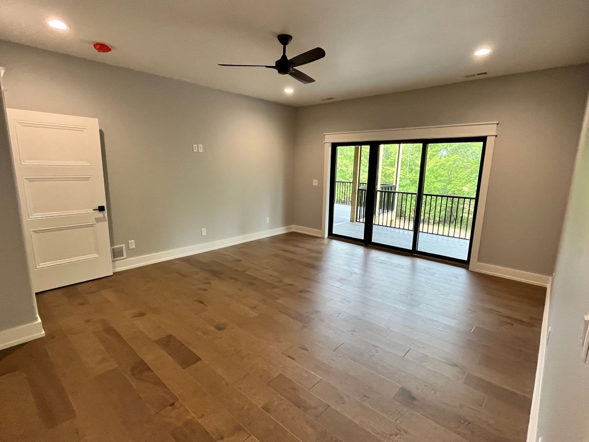 An empty living room with hardwood floors and a ceiling fan.