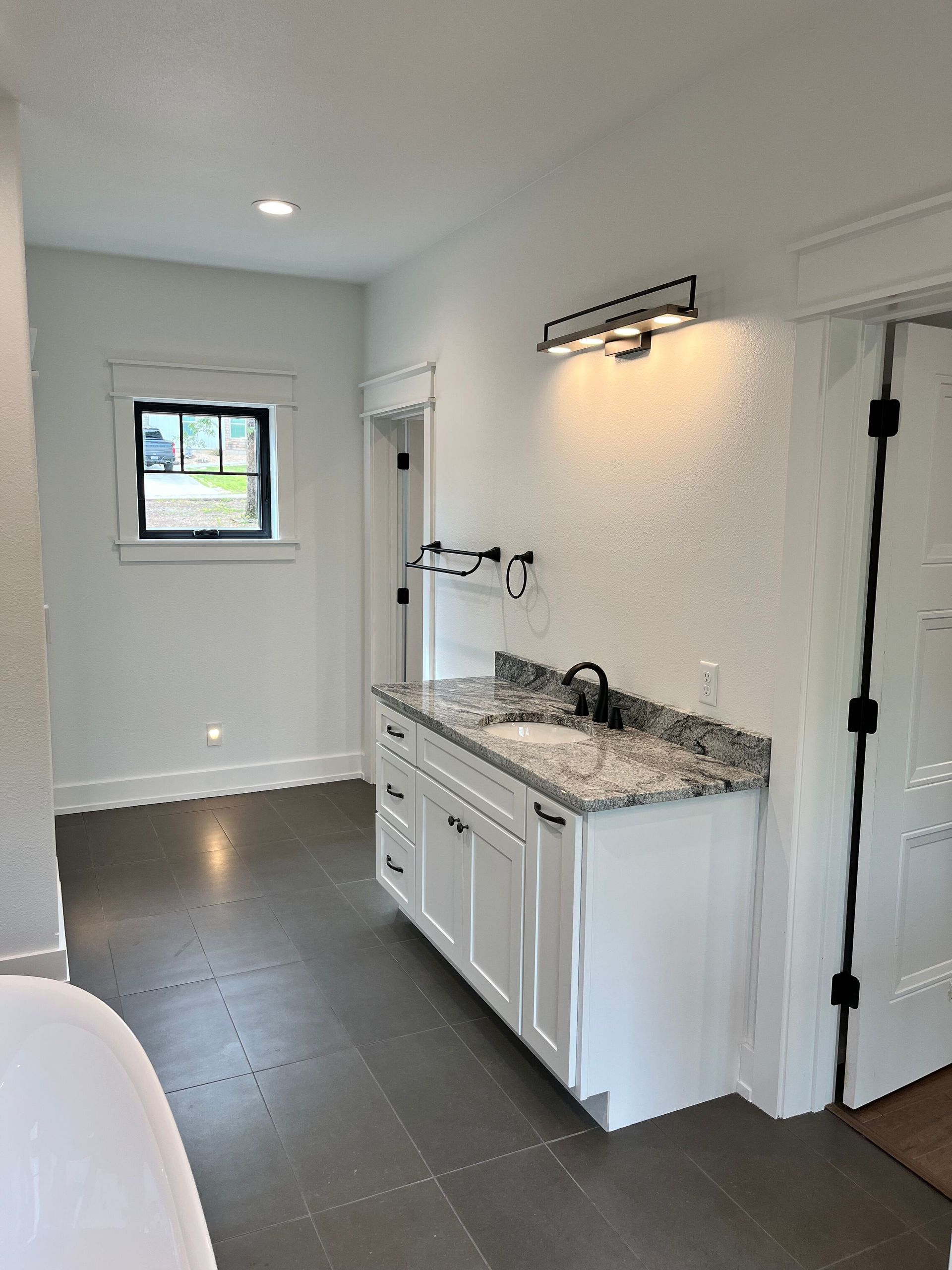 A bathroom with a sink , cabinets , and a window.