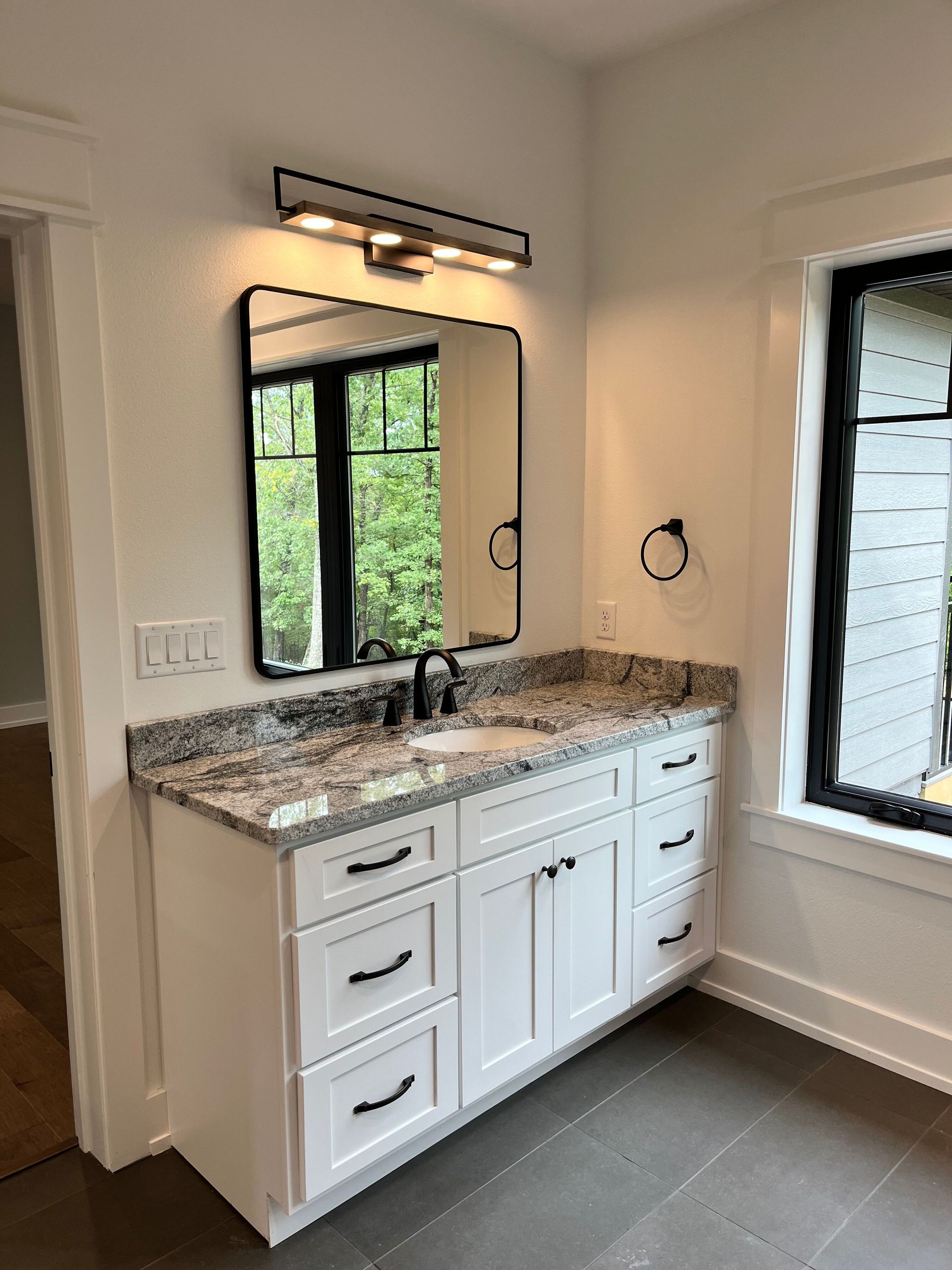 A bathroom with a sink , mirror and window.