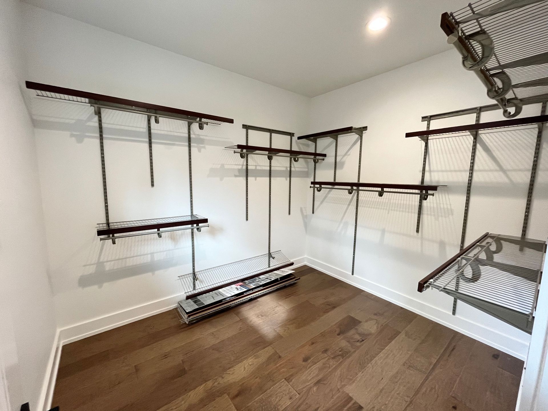 A walk in closet with lots of shelves and a wooden floor.
