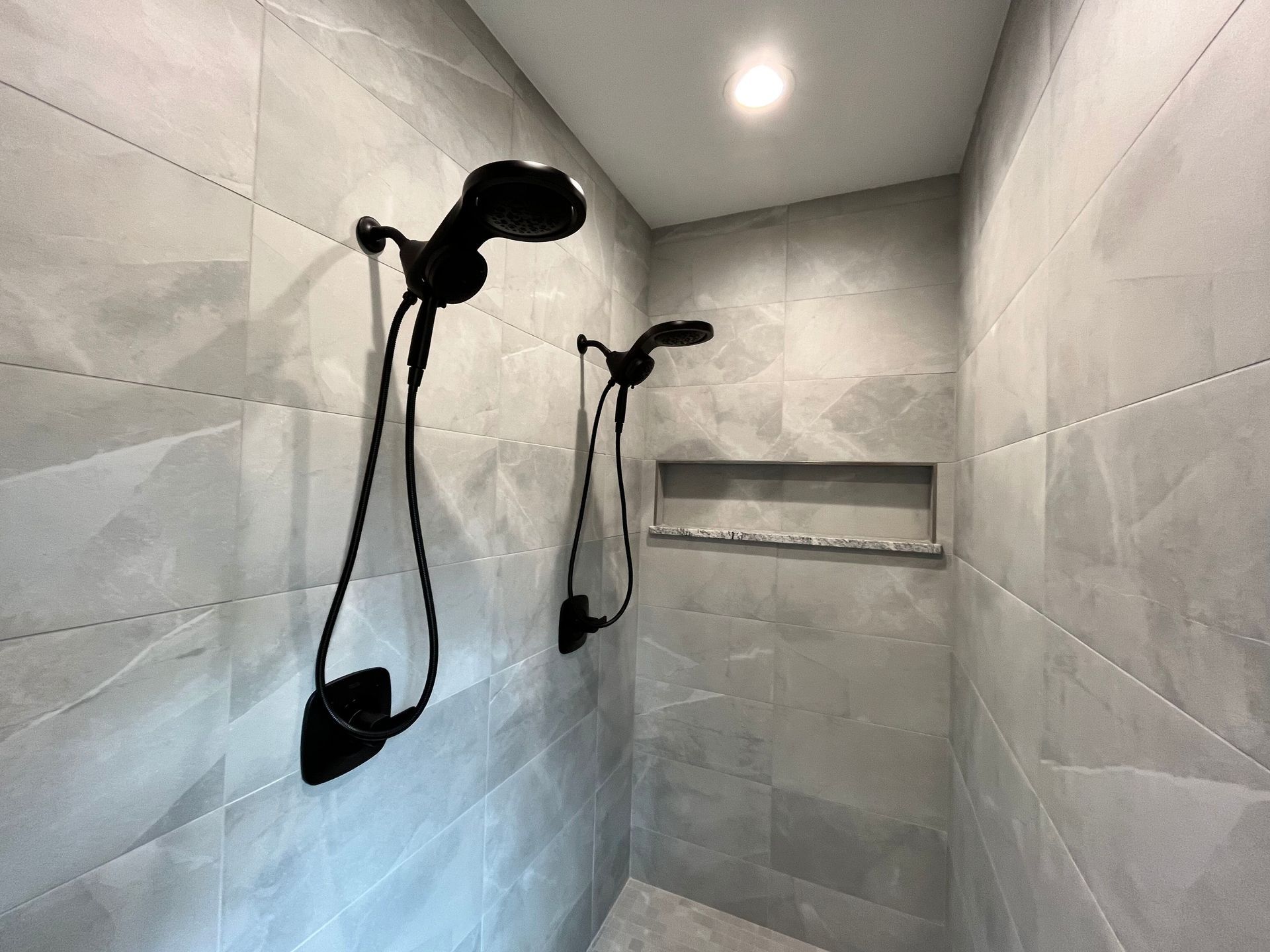 A bathroom with two shower heads hanging from the ceiling.