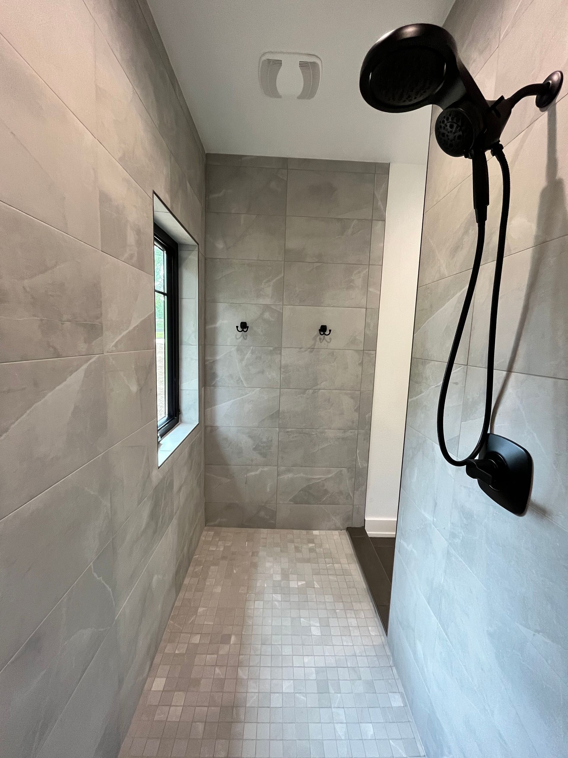 A bathroom with a shower head and a window.