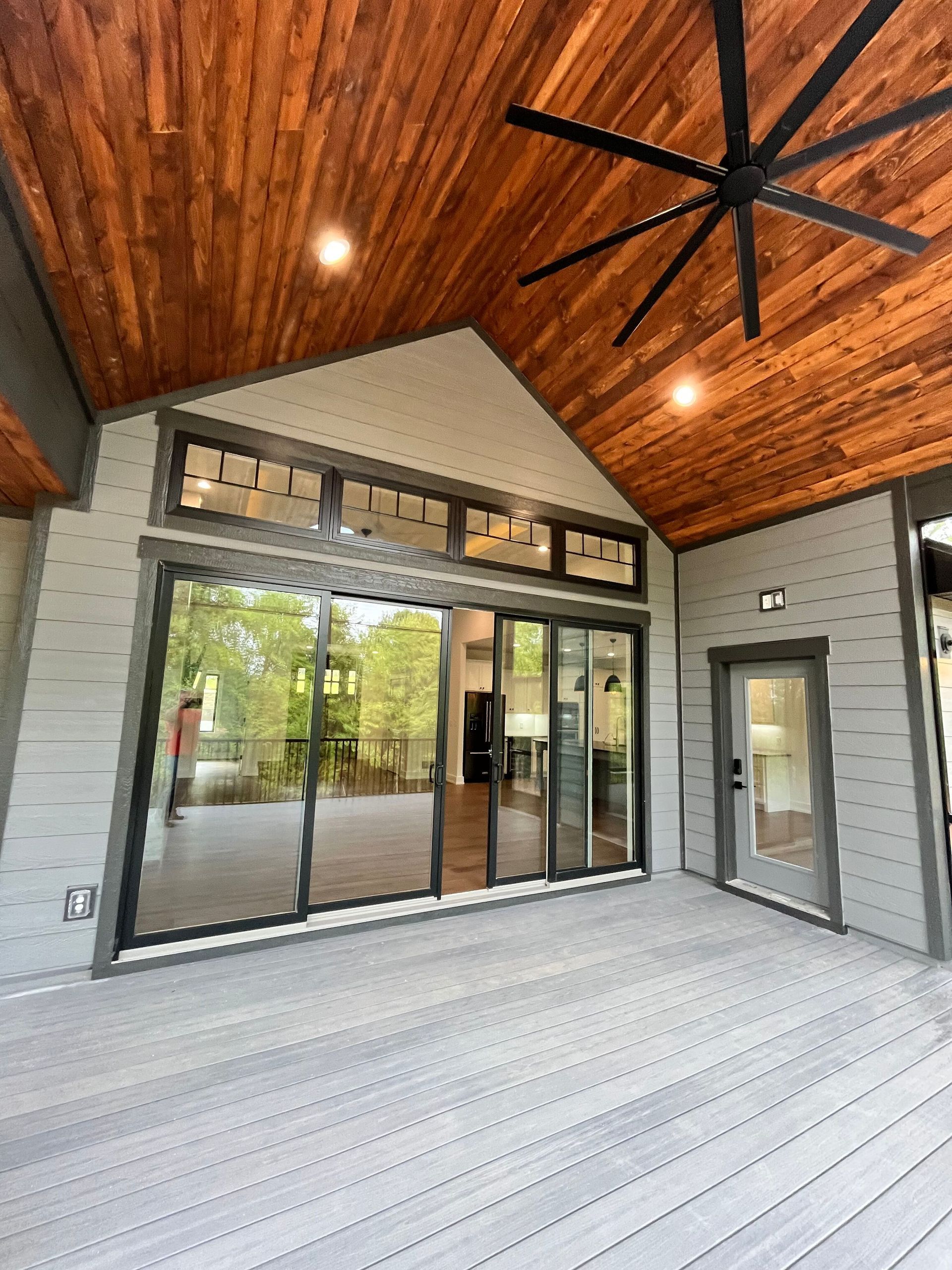 A large deck with a ceiling fan and sliding glass doors