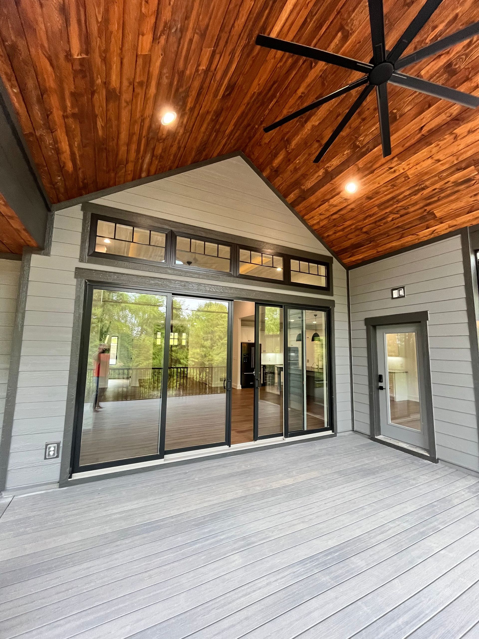 A large deck with a ceiling fan and sliding glass doors