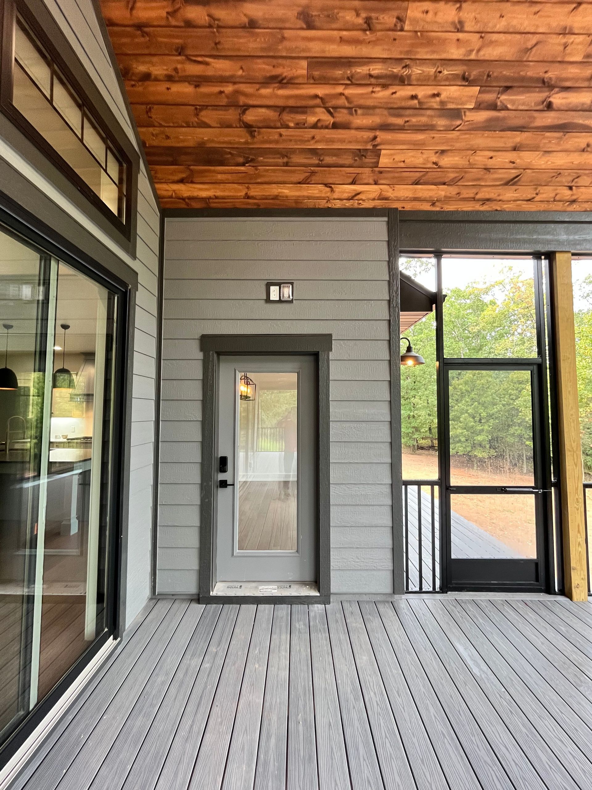 A screened in porch with a door and a wooden ceiling.