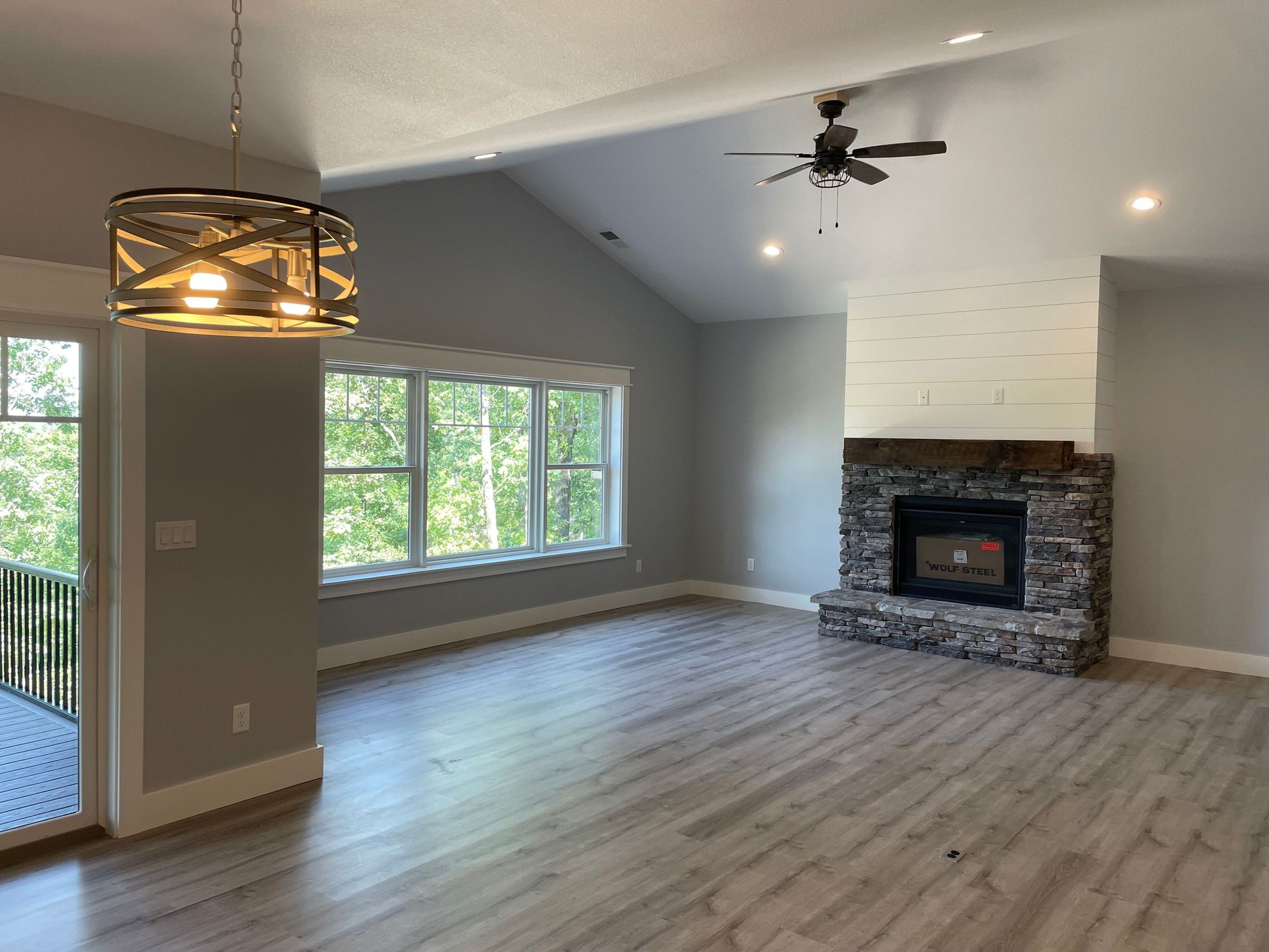 An empty living room with a fireplace and a ceiling fan.