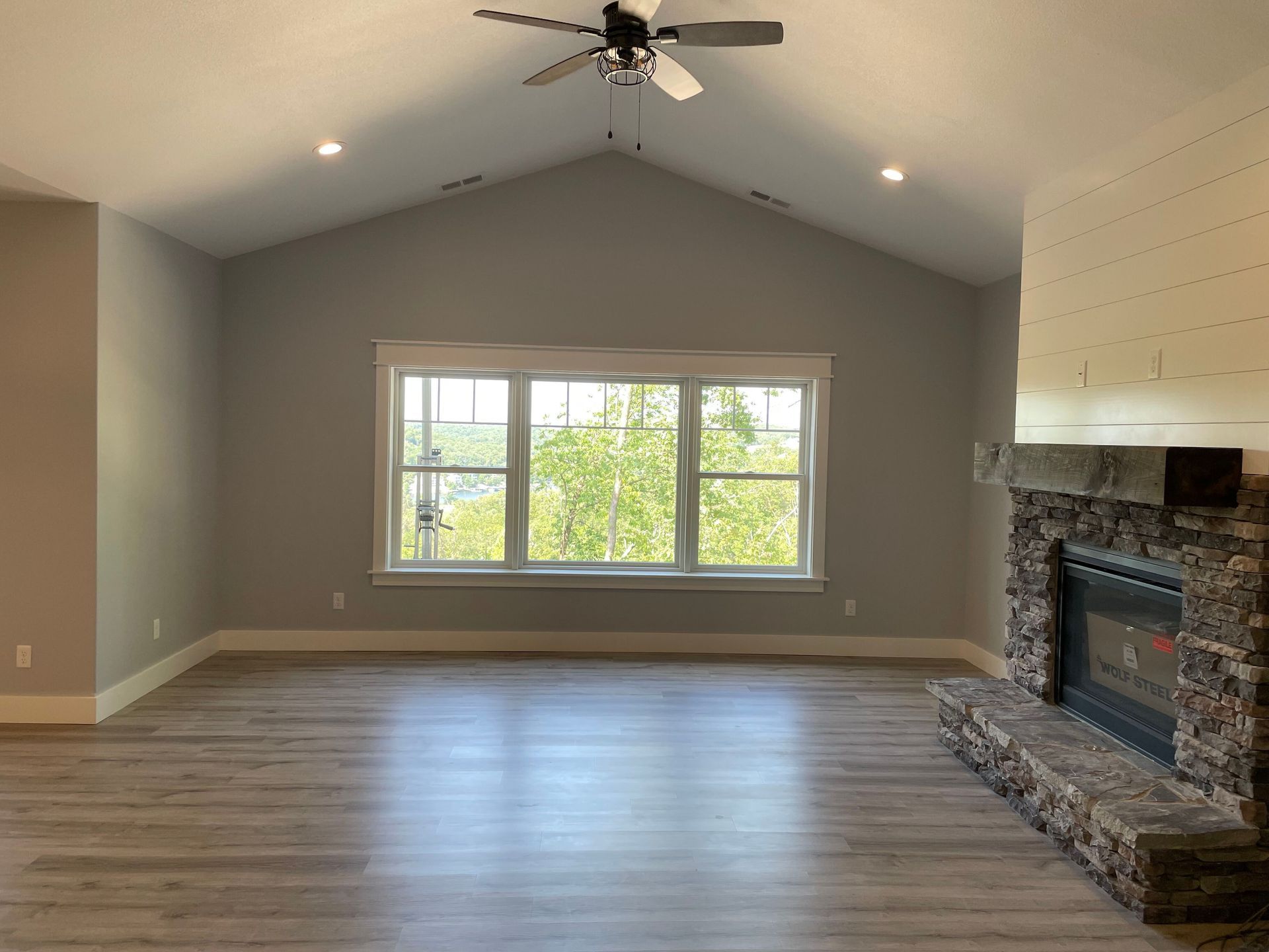 An empty living room with a fireplace and ceiling fan.