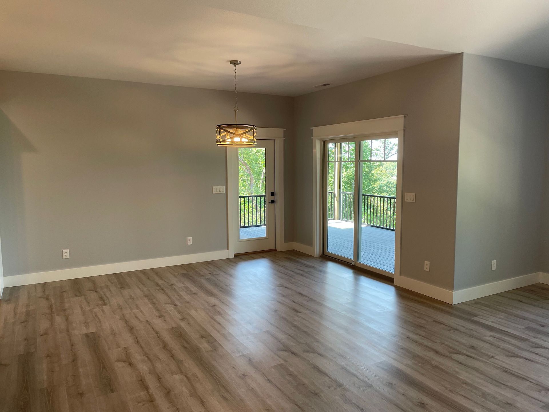 An empty living room with hardwood floors and sliding glass doors leading to a balcony.
