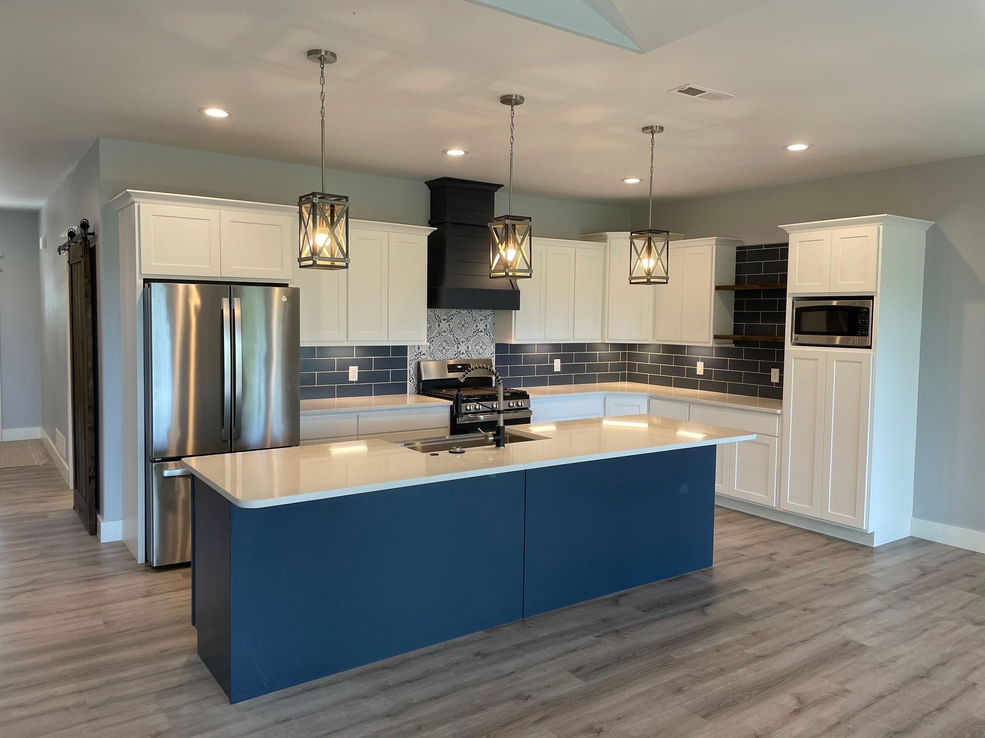 A kitchen with blue cabinets , white cabinets , stainless steel appliances and a large island.