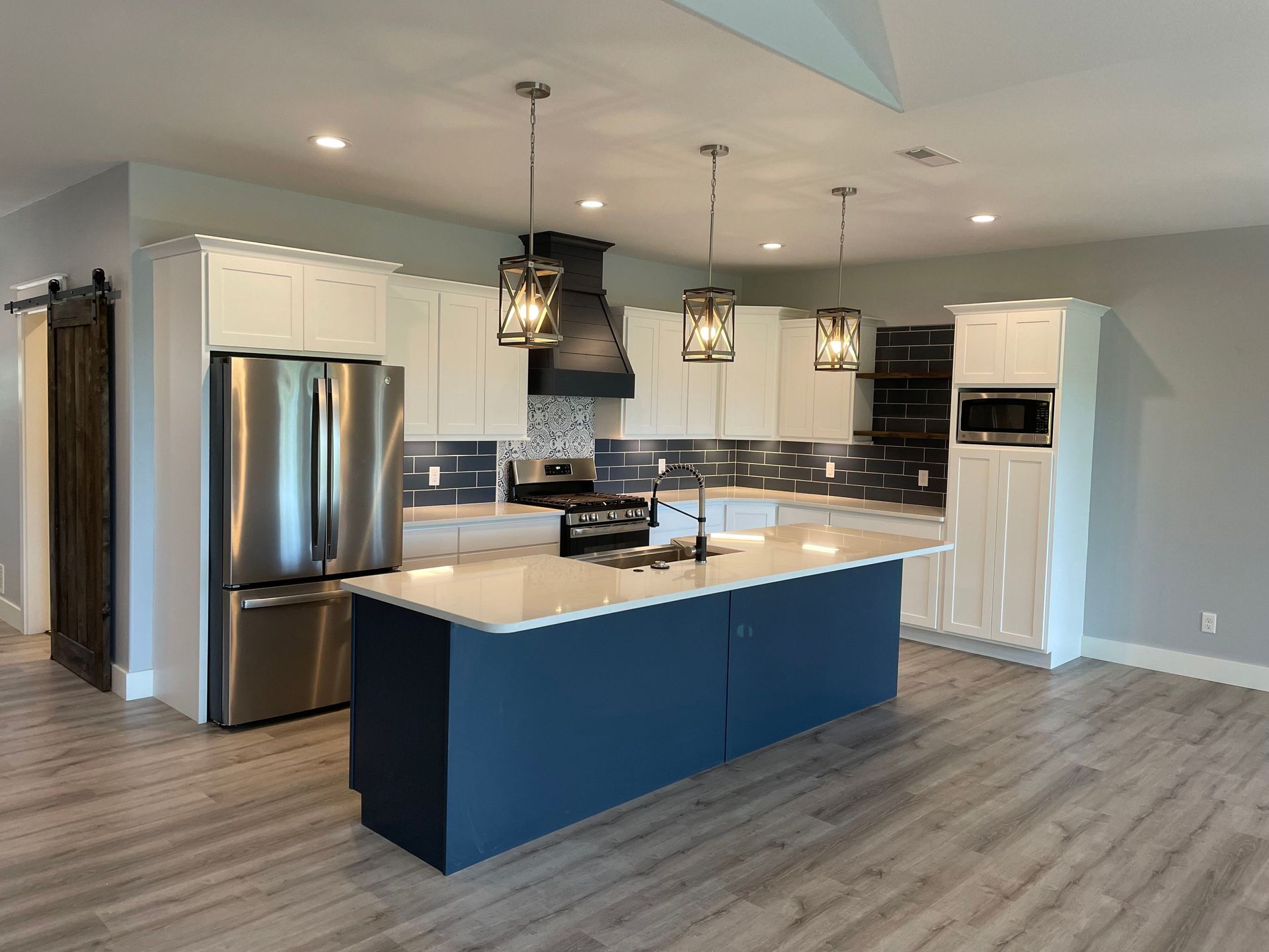 A kitchen with stainless steel appliances and a large island in the middle.