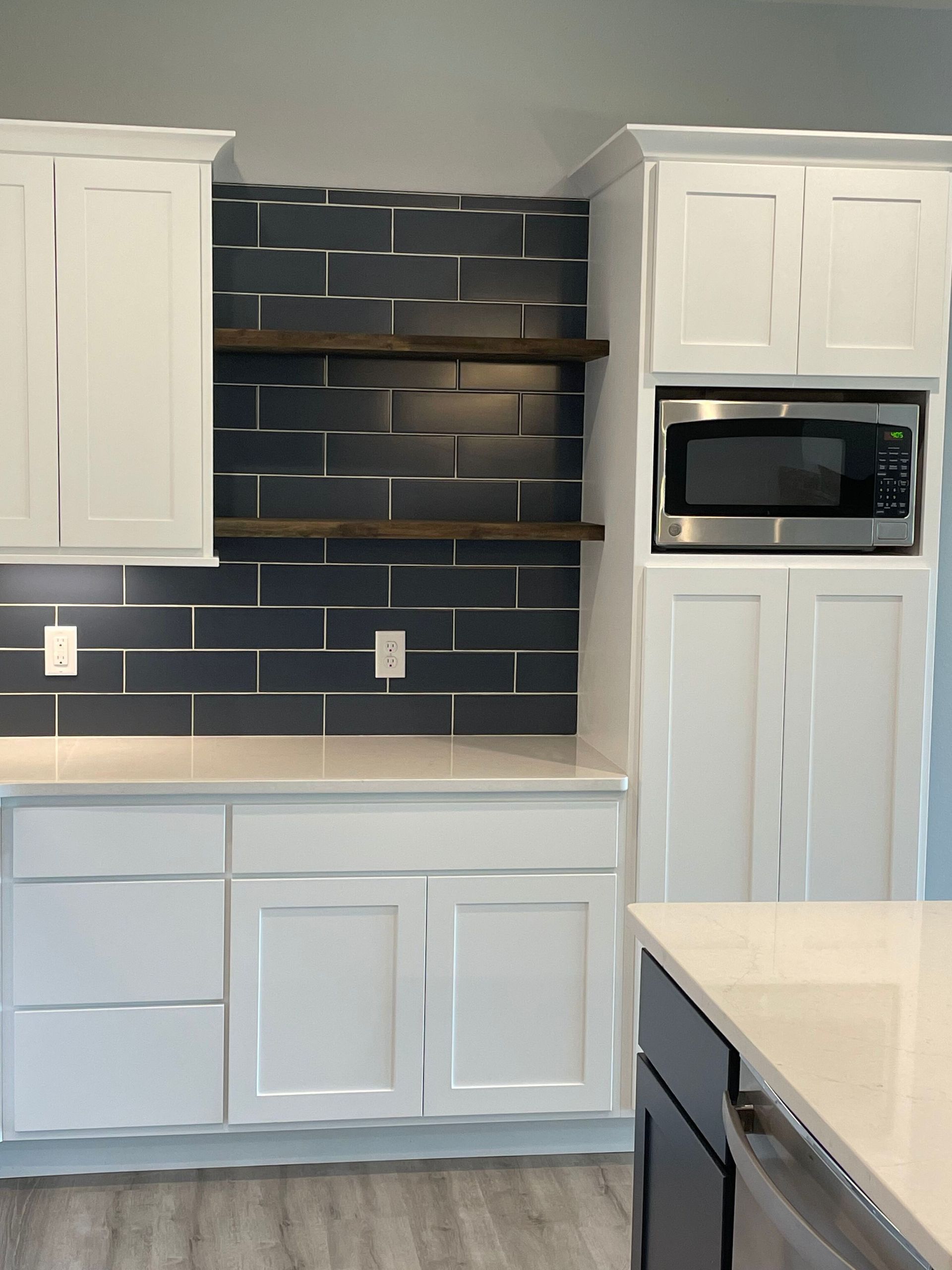 A kitchen with white cabinets and a stainless steel microwave