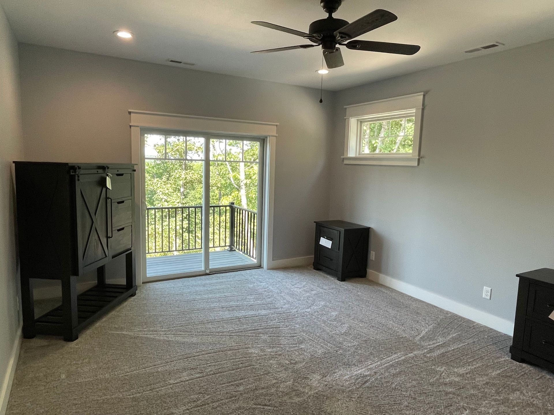 An empty room with a ceiling fan and a sliding glass door.