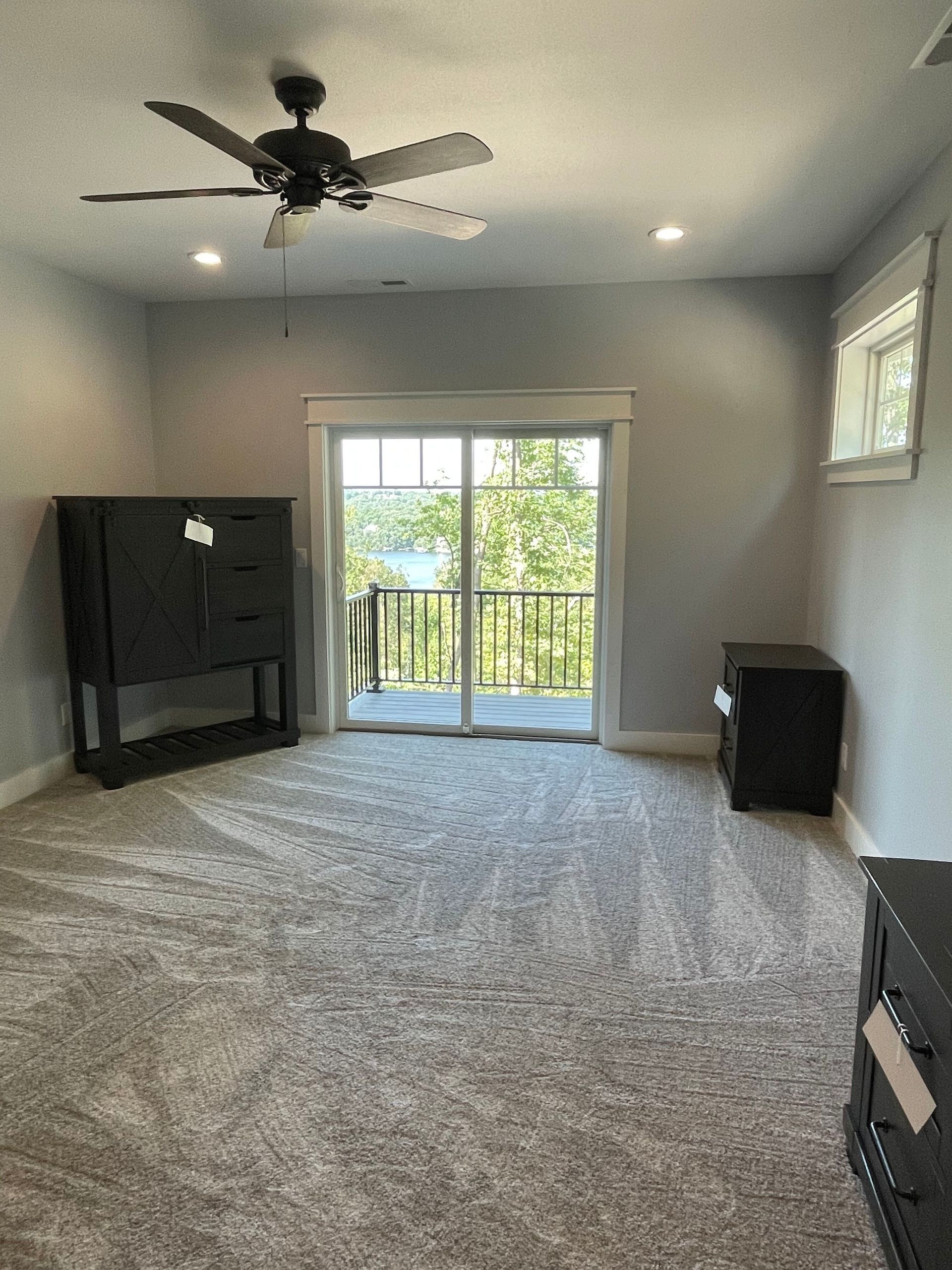 An empty room with a ceiling fan and a sliding glass door.
