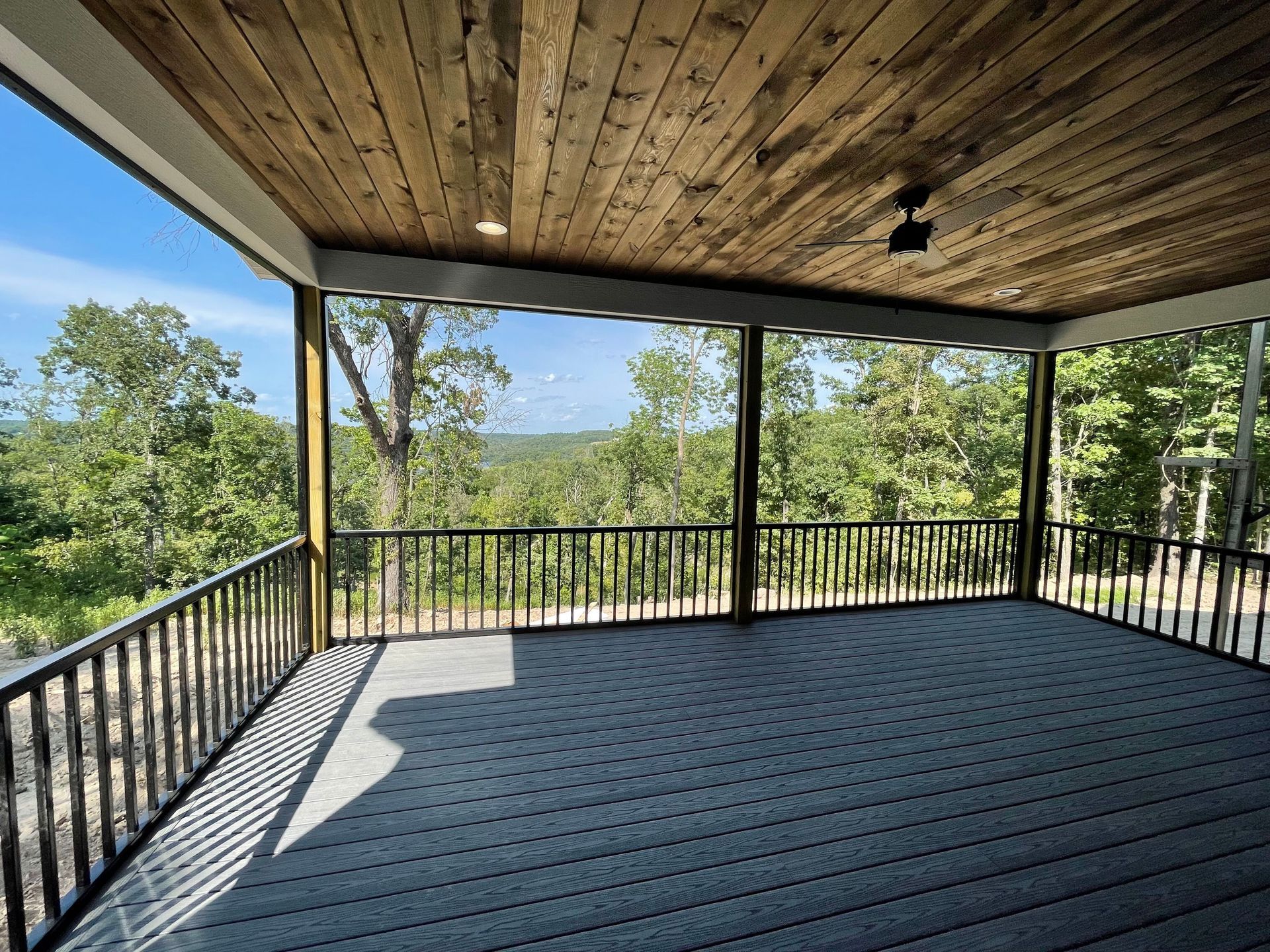 A screened in porch with a view of trees and mountains.