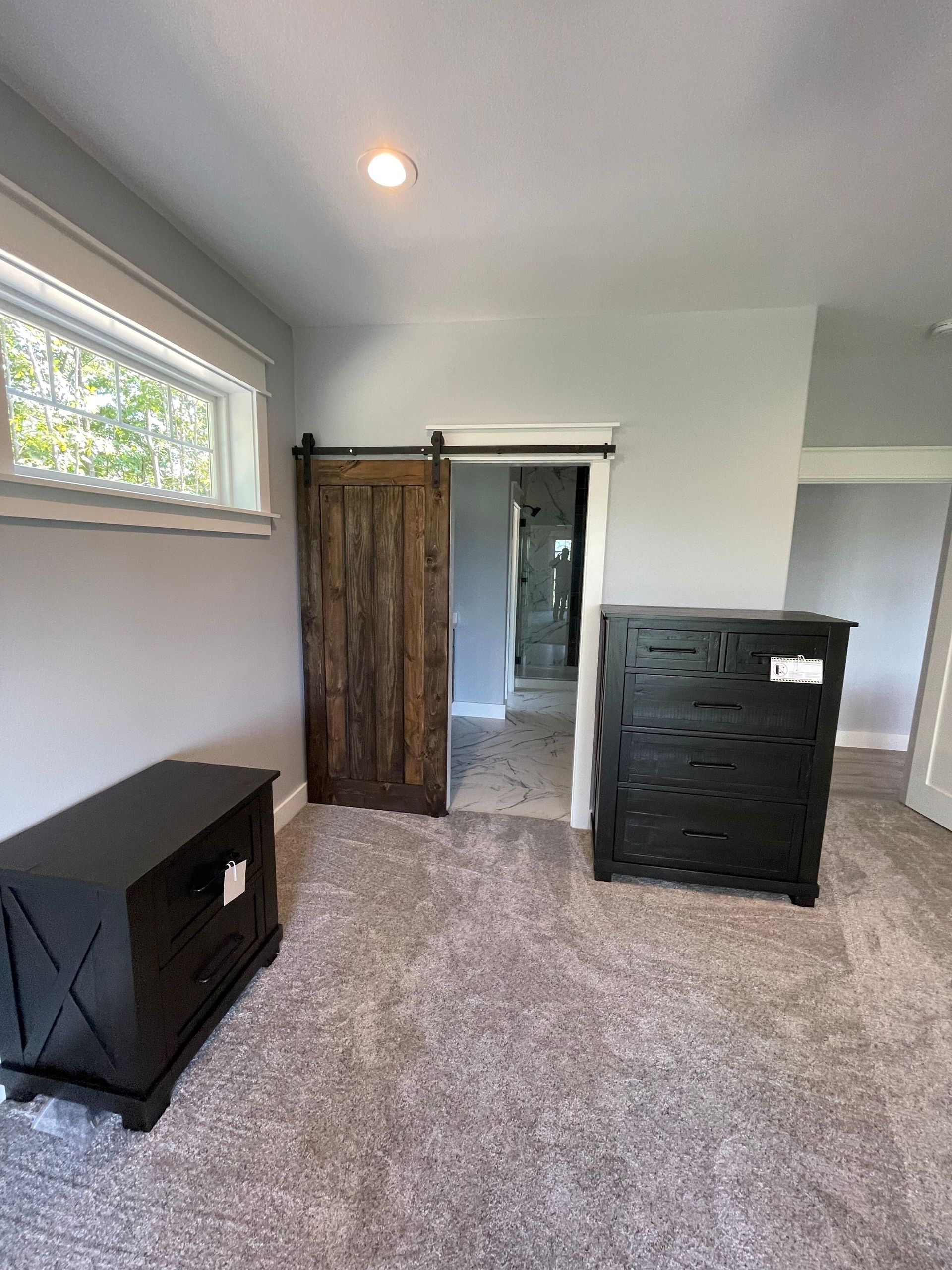A bedroom with a sliding barn door , dresser and nightstand.