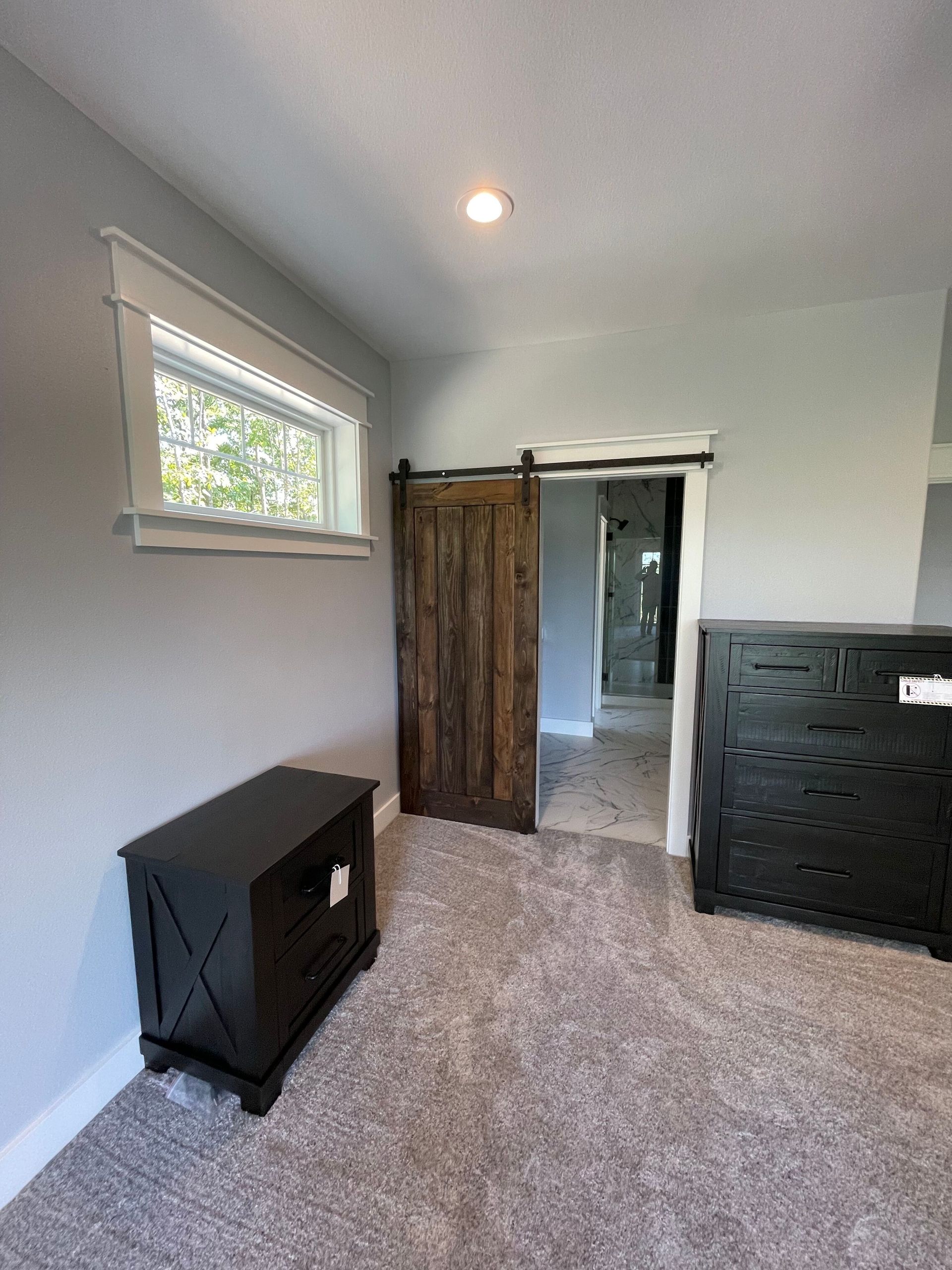 A bedroom with a sliding barn door and a window.