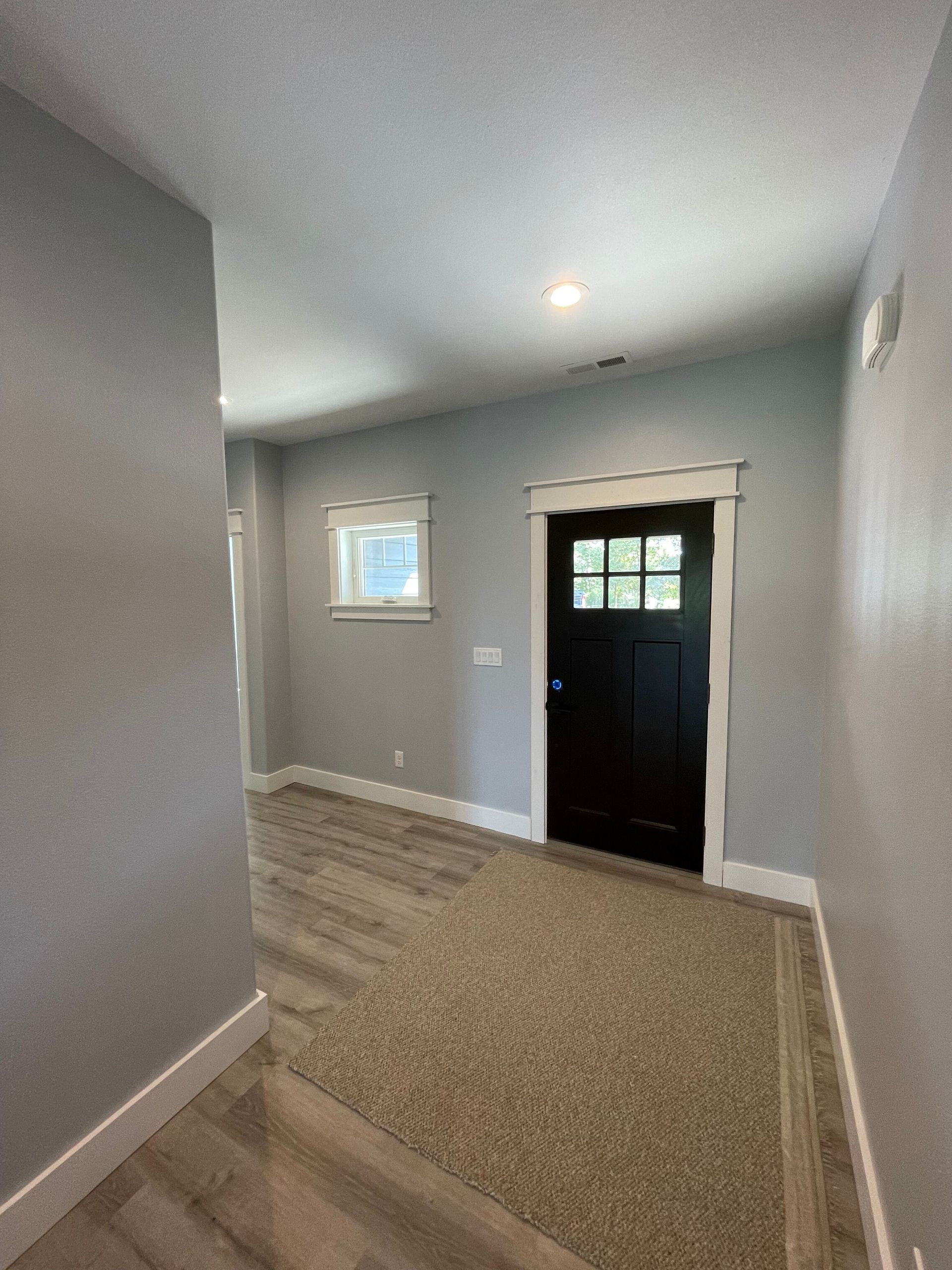 A hallway with a black door and a window