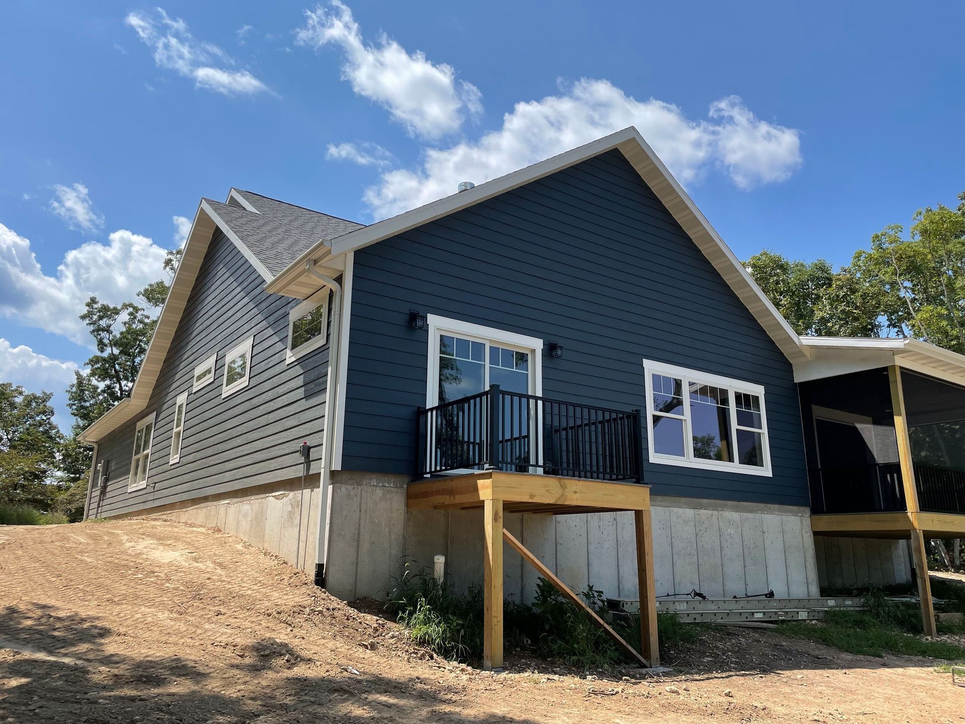 A blue house with a screened in porch is being built.