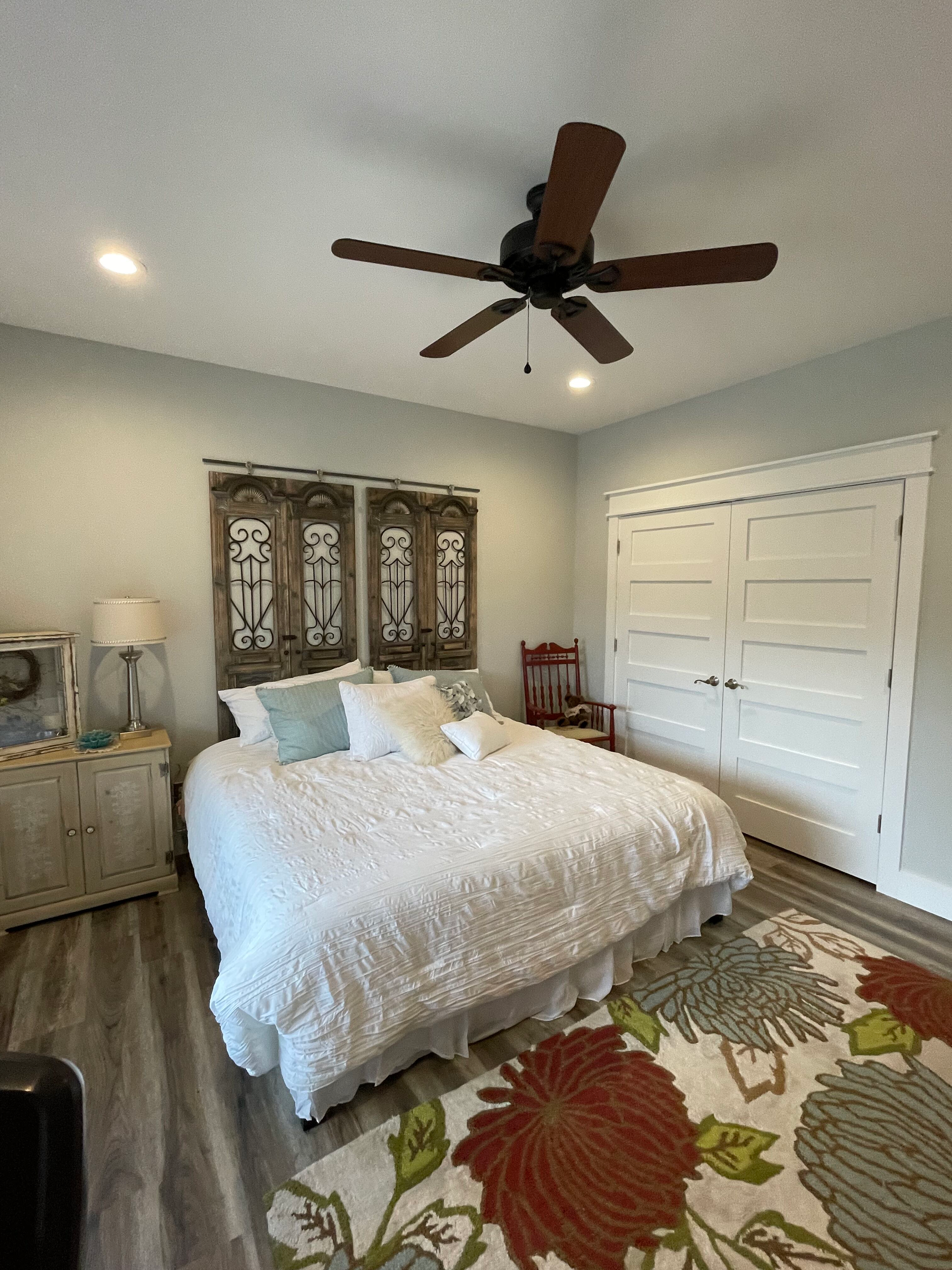A bedroom with a large bed and a ceiling fan.