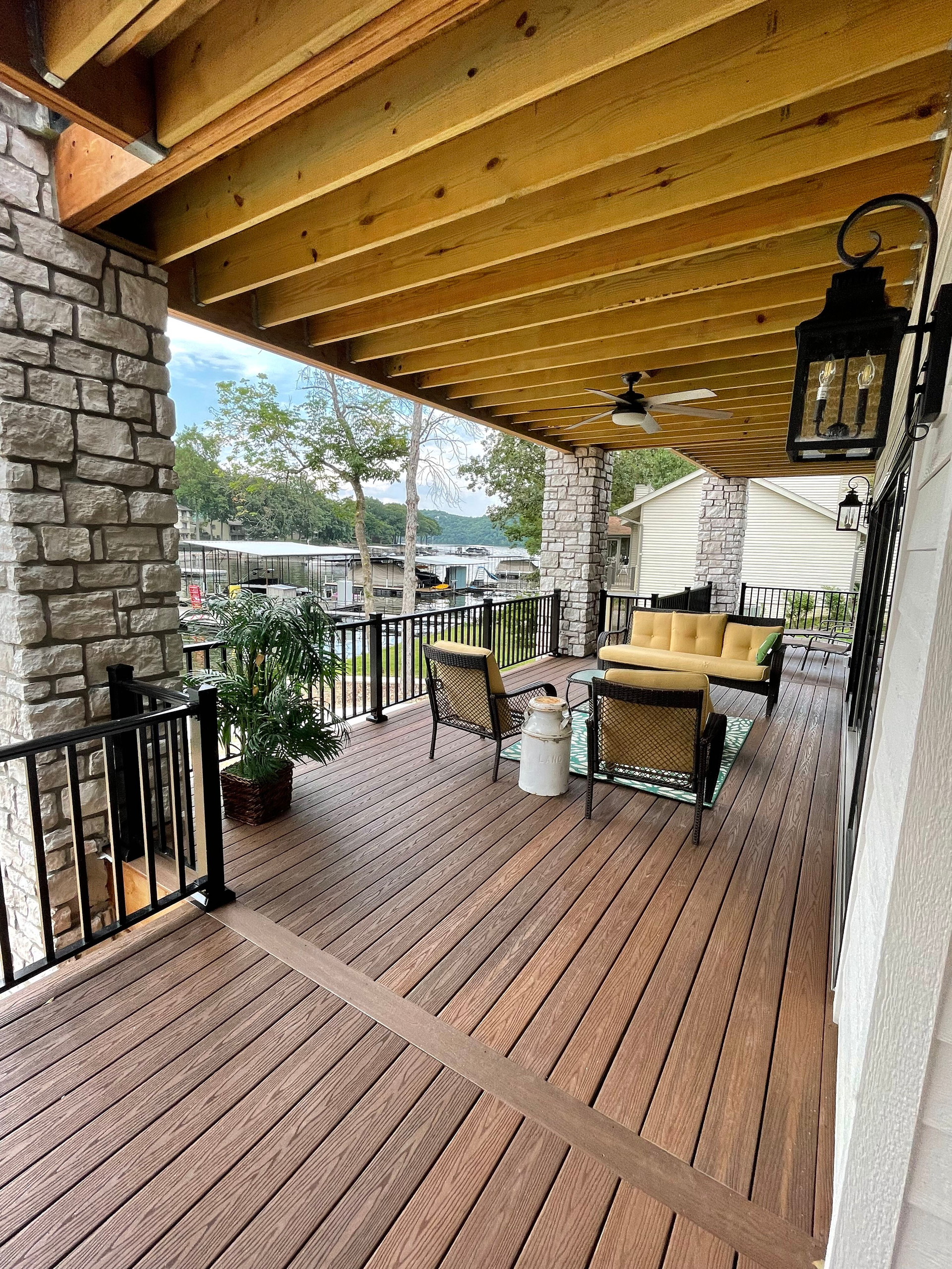 A large wooden deck with furniture and a ceiling fan.