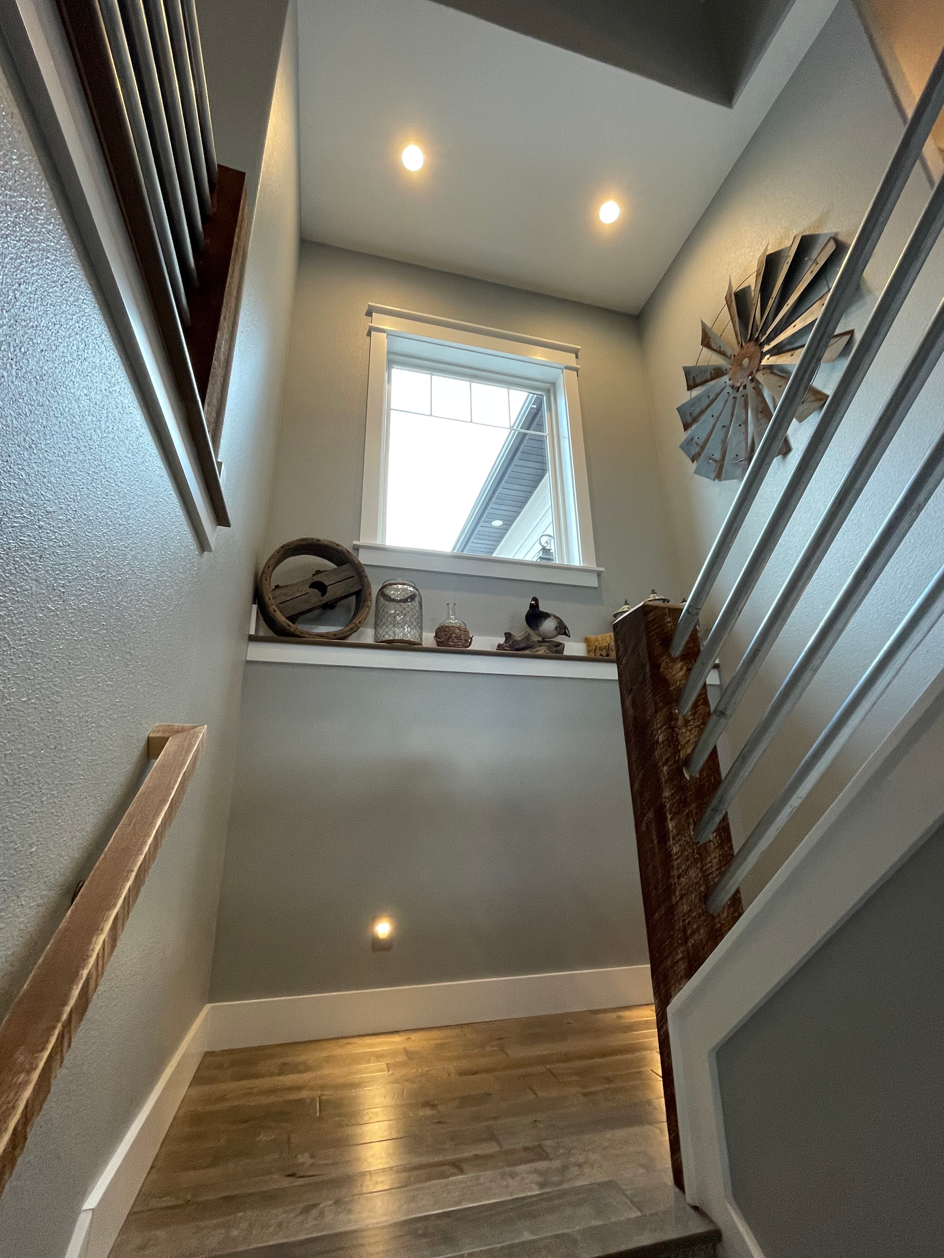 A staircase with a window and a fan on the wall.