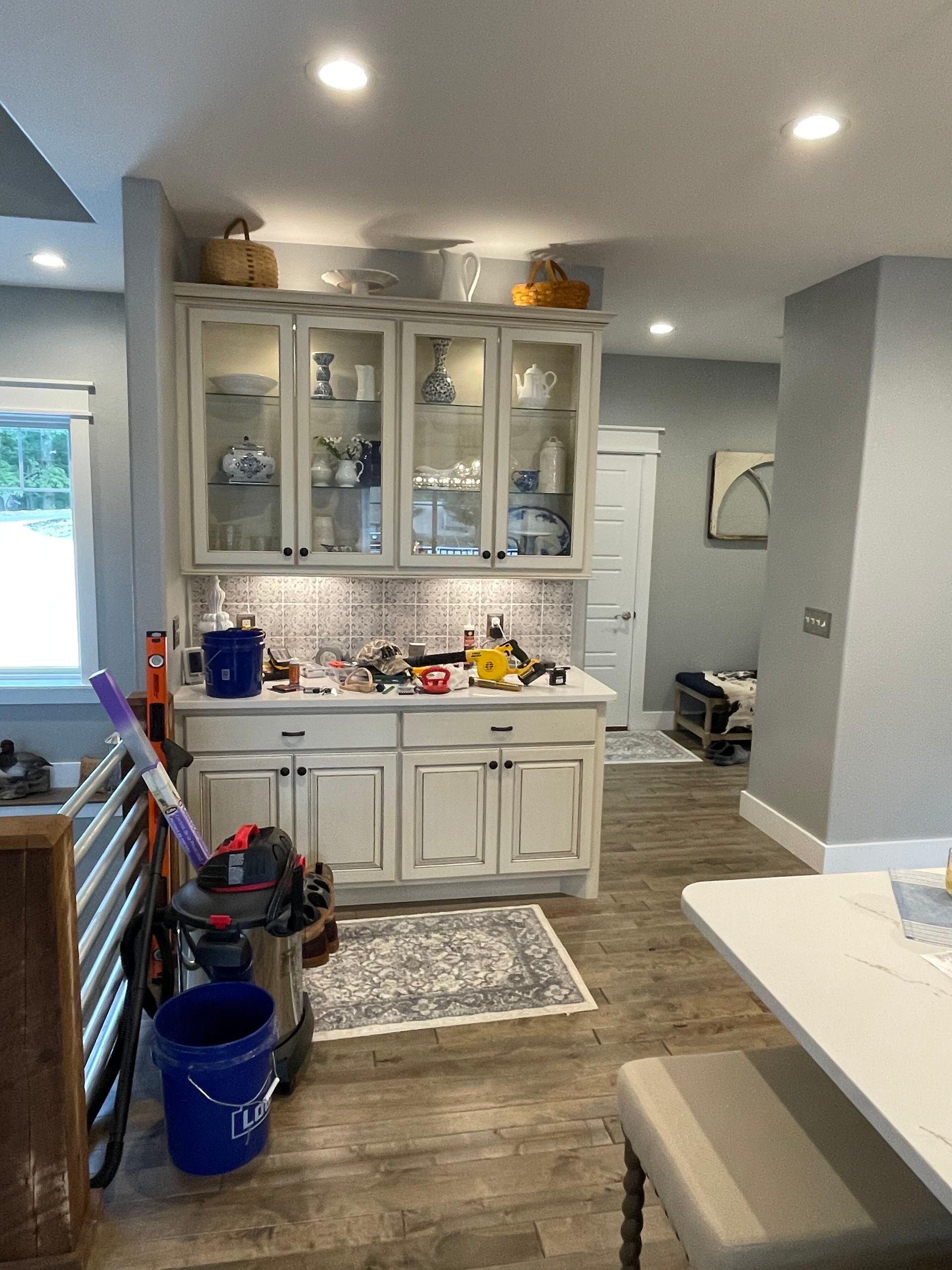 A kitchen with white cabinets and a vacuum cleaner