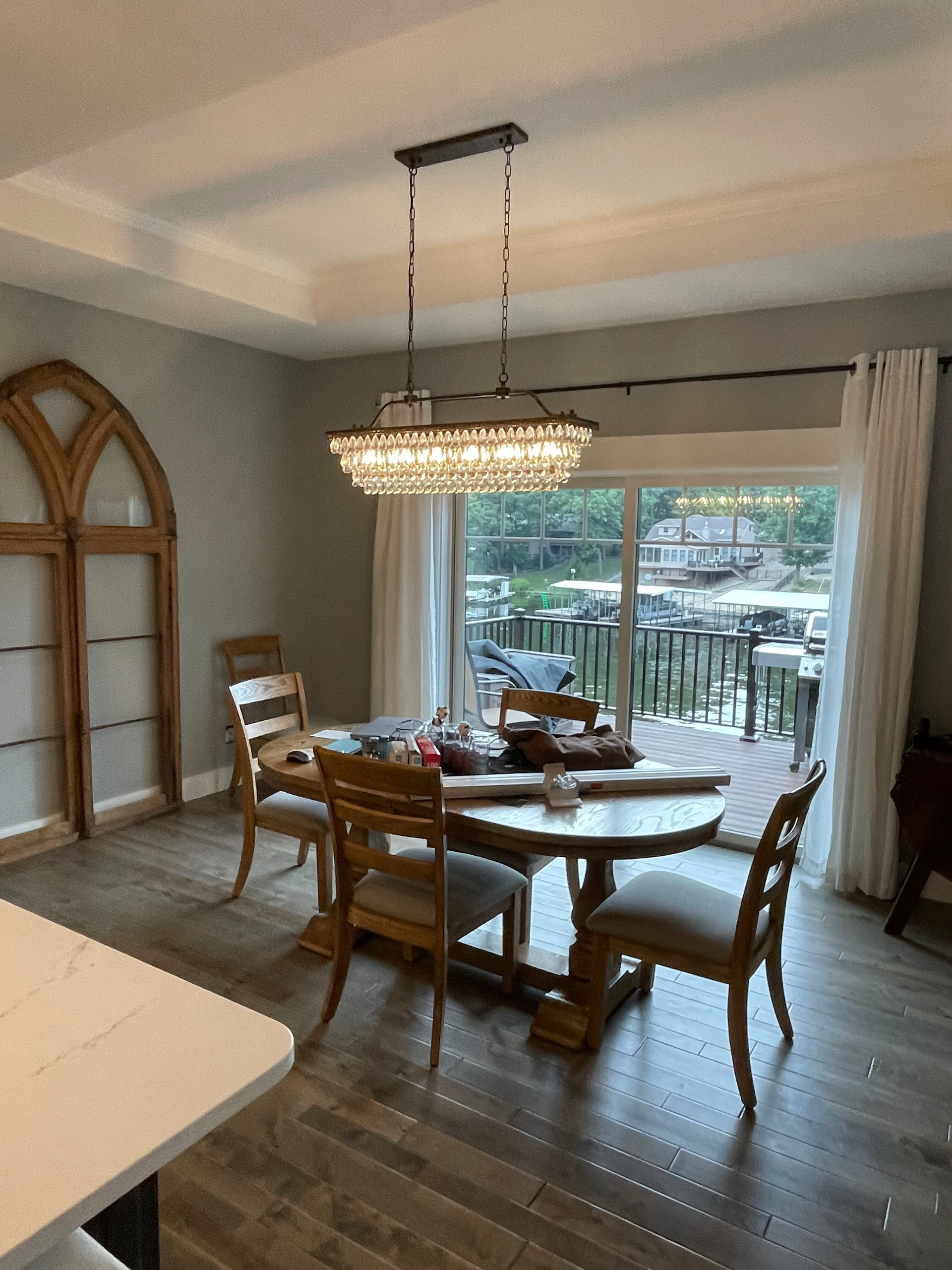 A dining room with a table and chairs and a chandelier hanging from the ceiling.