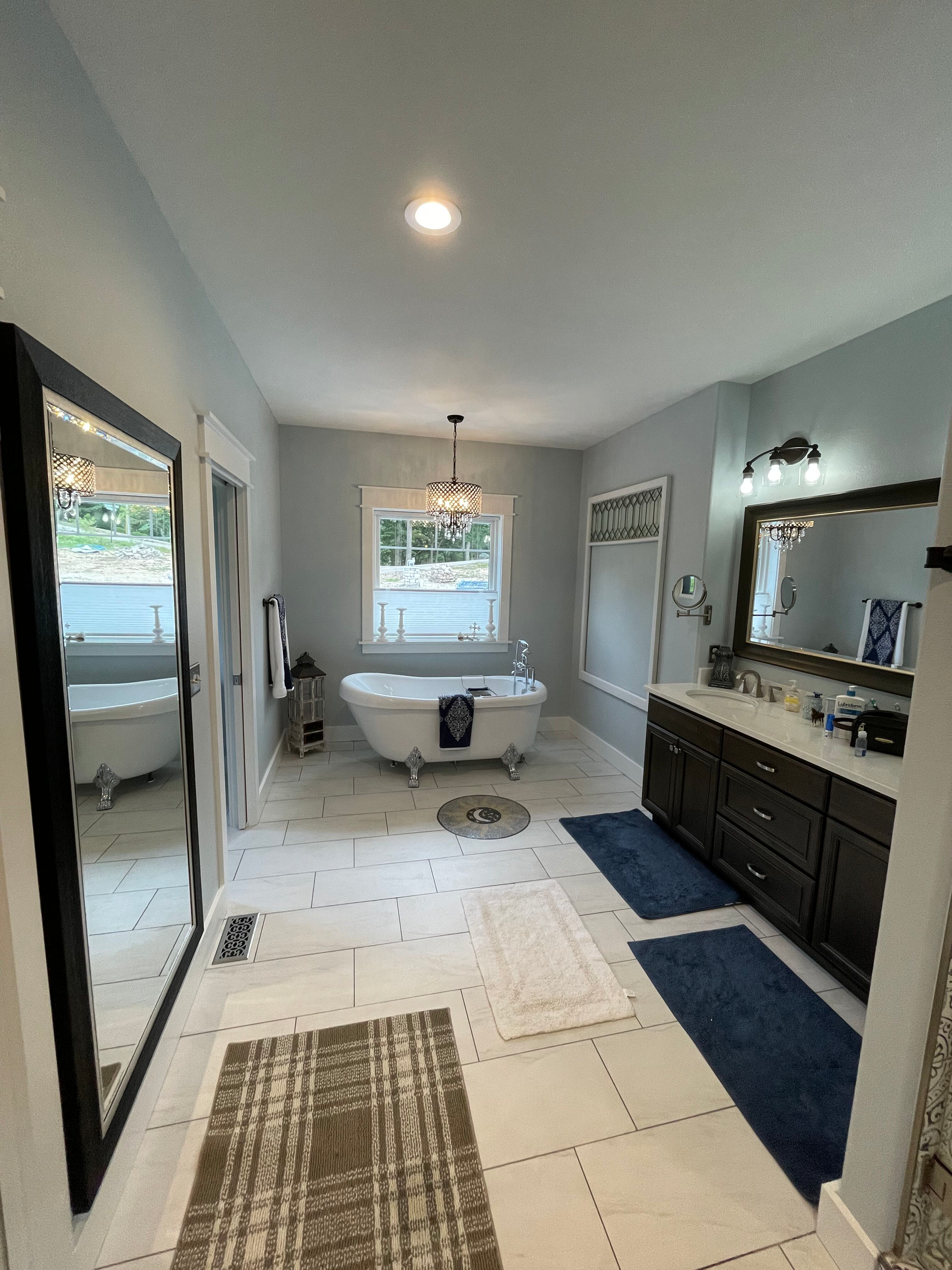 A bathroom with a tub , sink , mirror and rug.